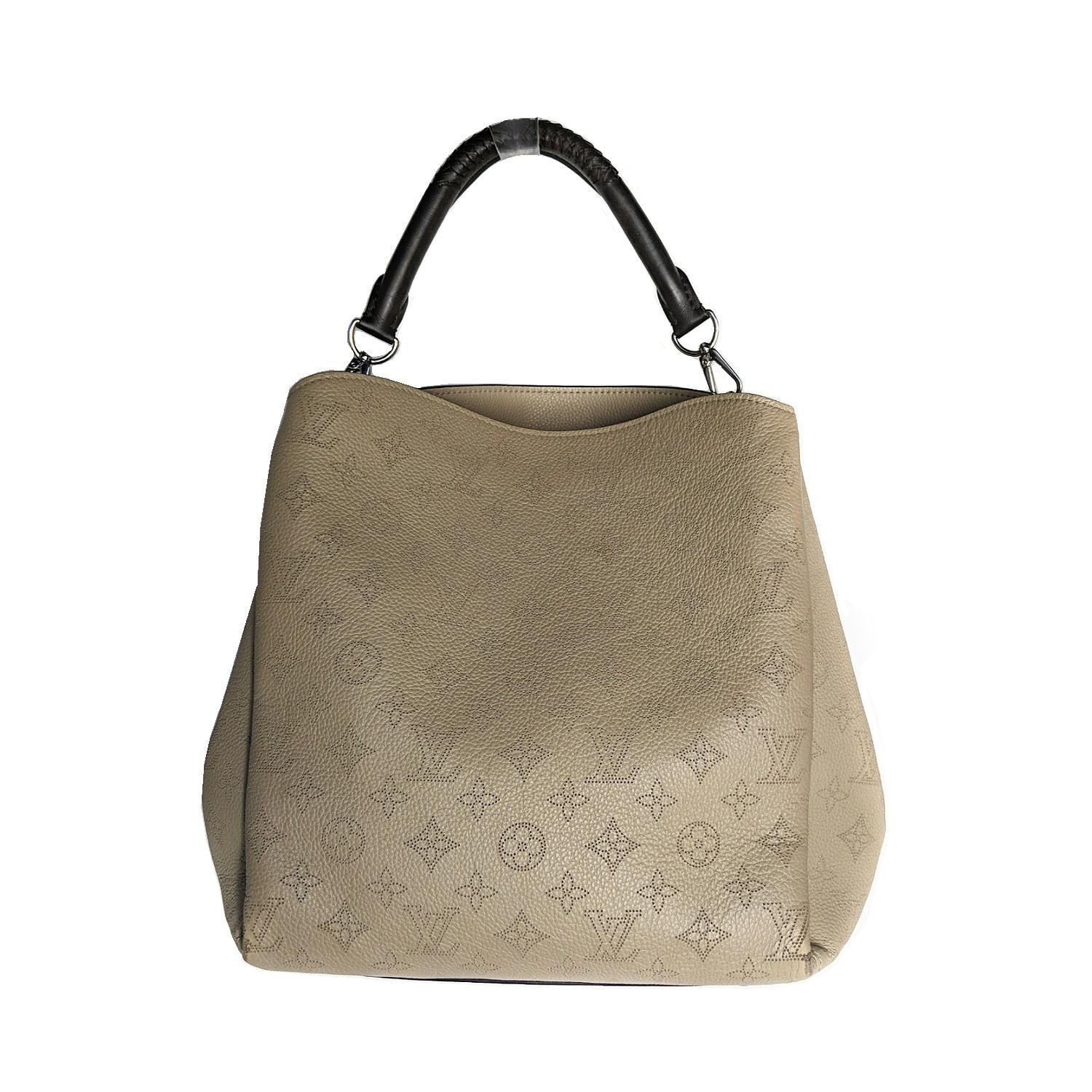 This is a tote that has a distinctive structure crafted of classic Louis Vuitton monogram in a beige leather. The short brown leather braided trim top handle is accompanied by an optional beige leather long shoulder strap. The top is open to an