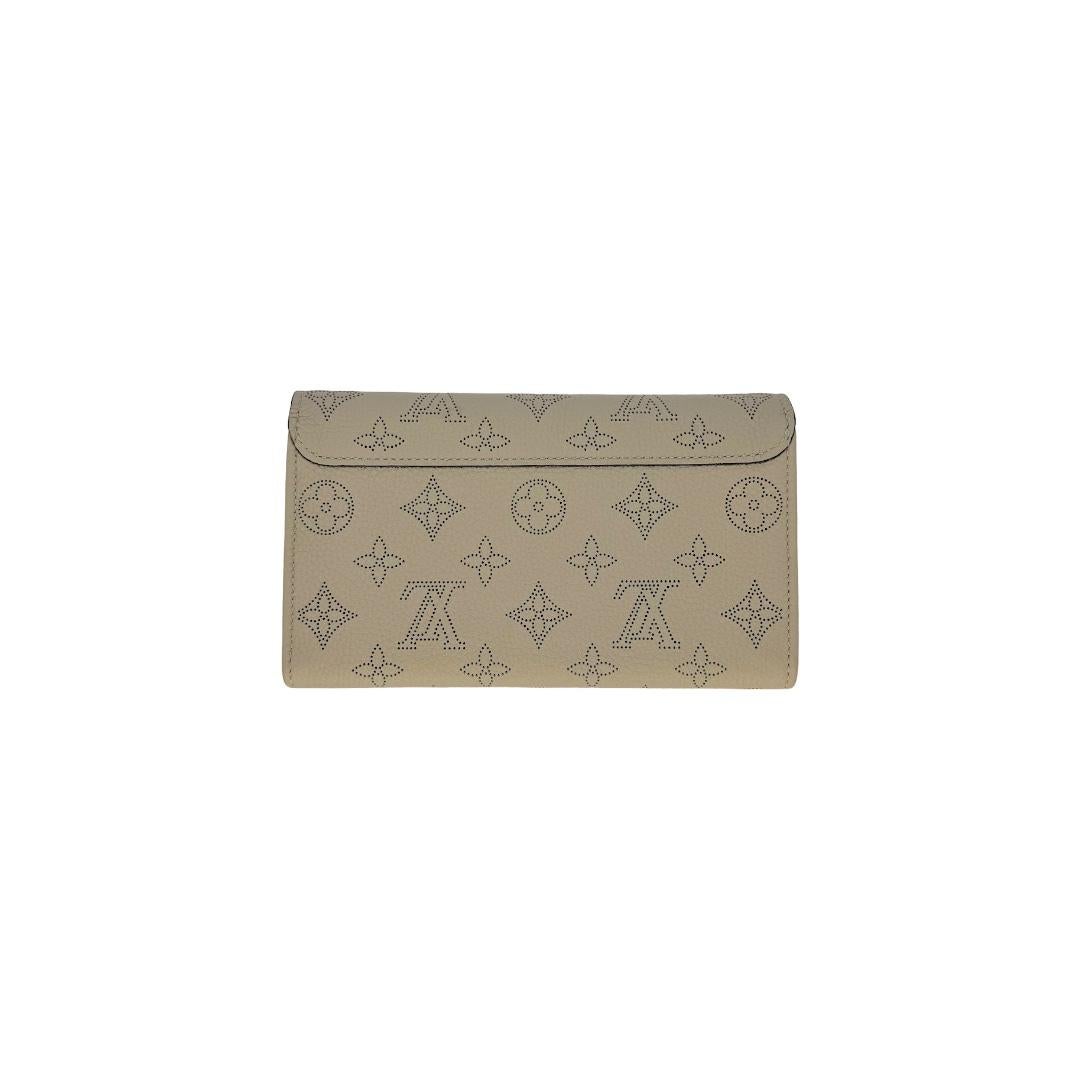 This very beautiful Louis Vuitton Iris Wallet was made in France in 2017, and it is finely crafted of Mahina perforated calf leather in Galet Grey with silver-tone hardware. It has a fold over flap with a snap closure that opens to calf leather