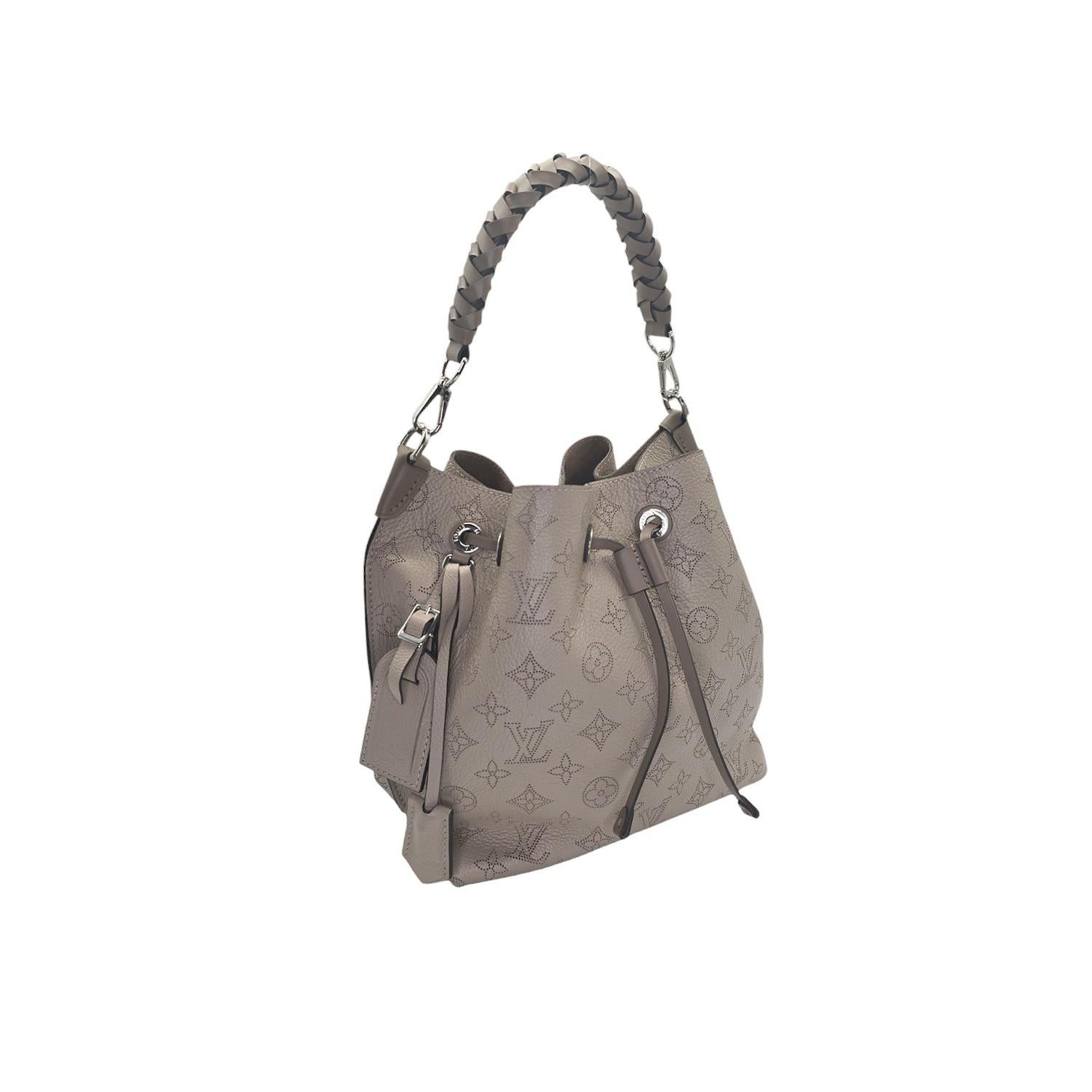 Date un capricho de lujo con el Monograma Mahina Muria Galet de Louis Vuitton. Fabricado en exquisita piel Mahina de color topo, este bolso bandolera tiene un cordón de ajuste, asa superior trenzada y herrajes de plata pulida. Un espacioso interior