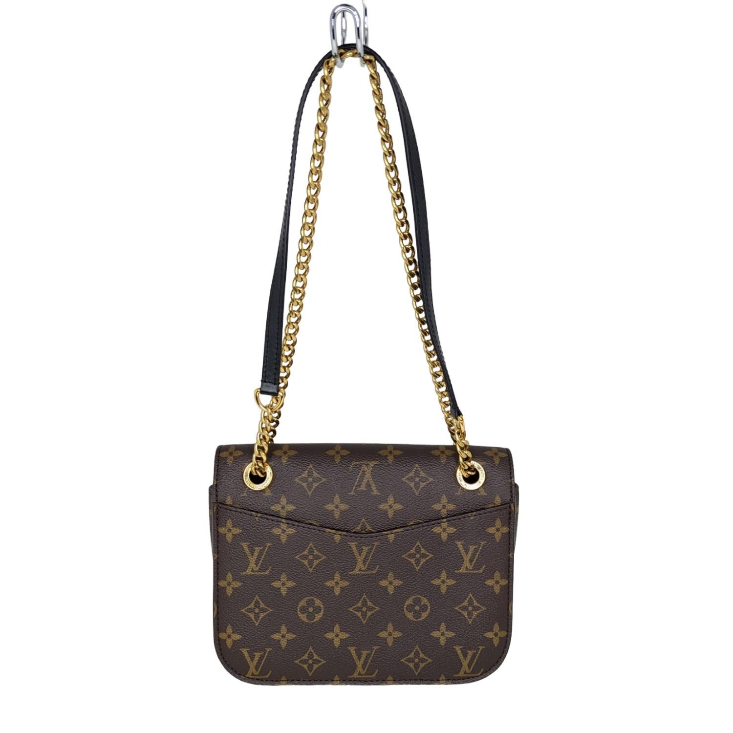 This handbag is crafted of classic Louis Vuitton monogram toile dark brown canvas. The bag features a gold chain shoulder strap with a black leather shoulder pad, a black and gold 