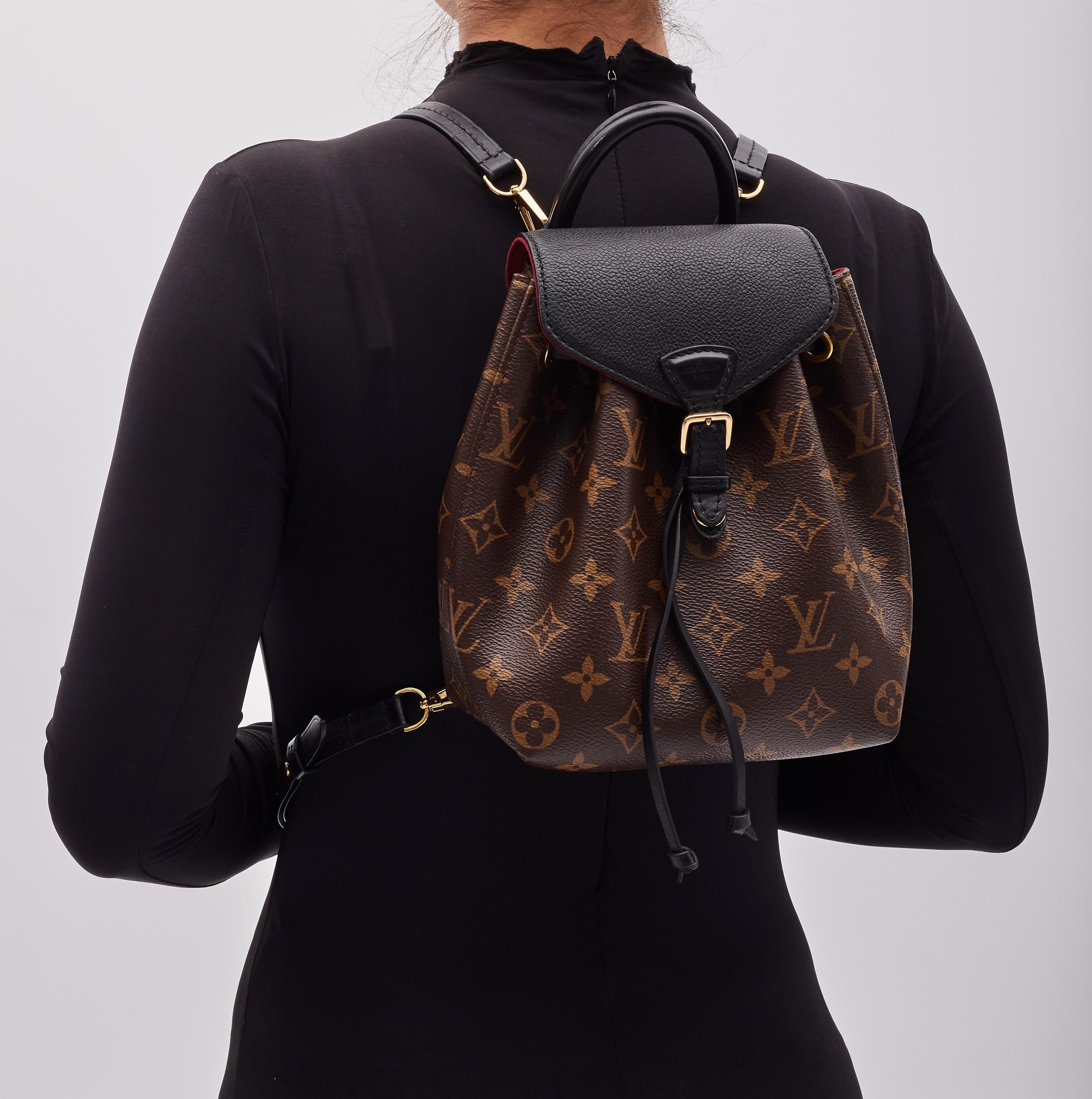 This stylish backpack is made from classic Louis Vuitton monogram with black leather details and finishes. The bag features adjustable straps, polished brass hardware, and opens with a belt buckle closure to a deep plum microfiber interior with a