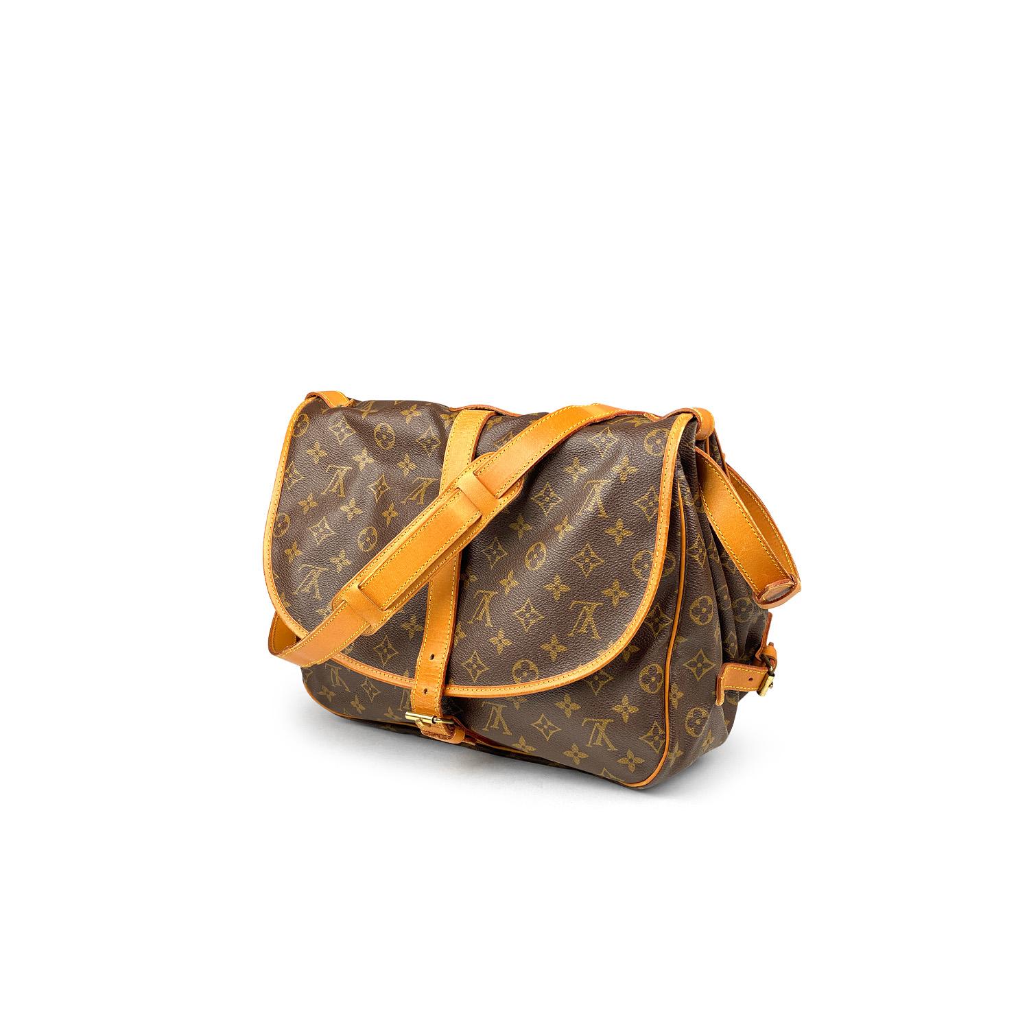 Brown and tan monogram coated canvas Louis Vuitton Saumur 35 with

- Brass hardware
- Tan vachetta trim
- Single flat shoulder strap featuring buckle adjustment
- Buckle expansions at sides
- Two compartments, tonal canvas lining, three slip pockets