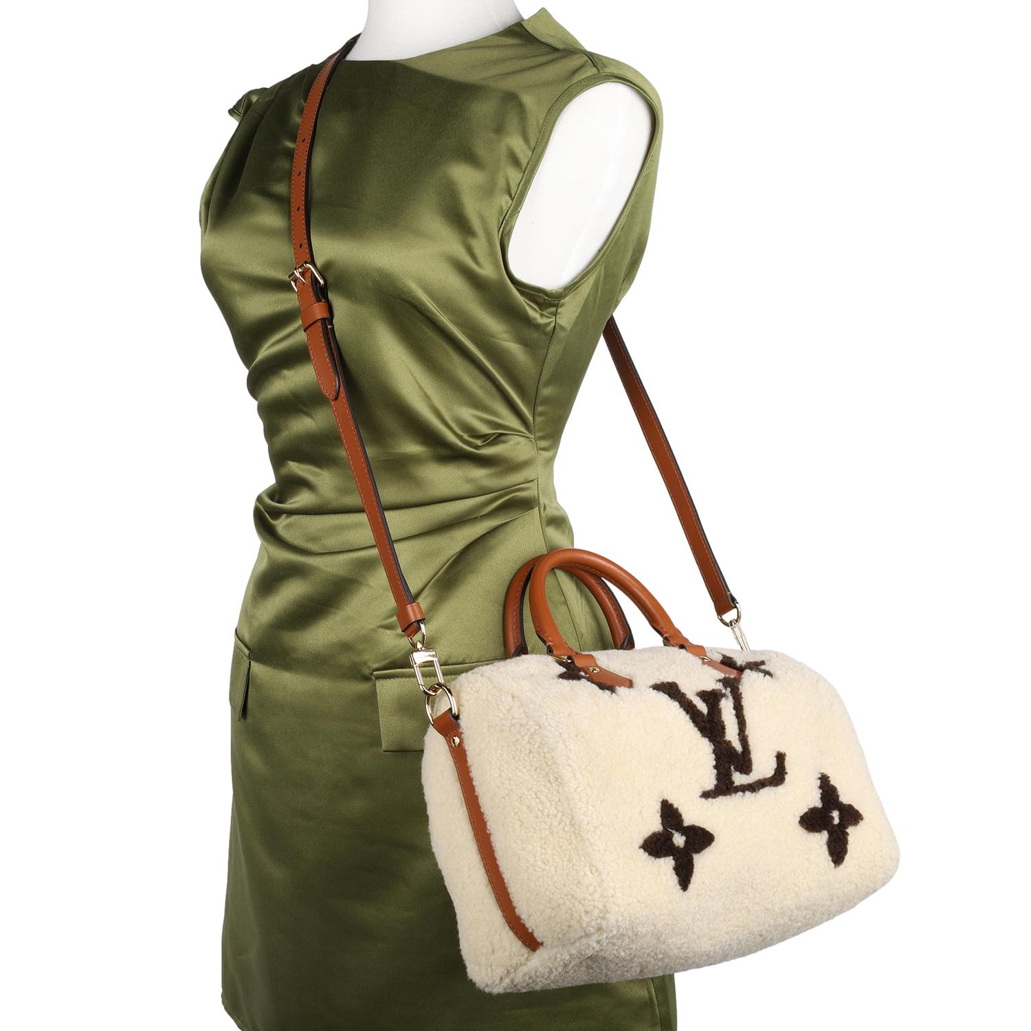 Experience true luxury with this authentic Louis Vuitton Monogram Shearling Speedy Bandoulière 25 in elegant cream and brown. Crafted from plush off-white shearling and adorned with the iconic brown Monogram pattern, this designer handbag is the