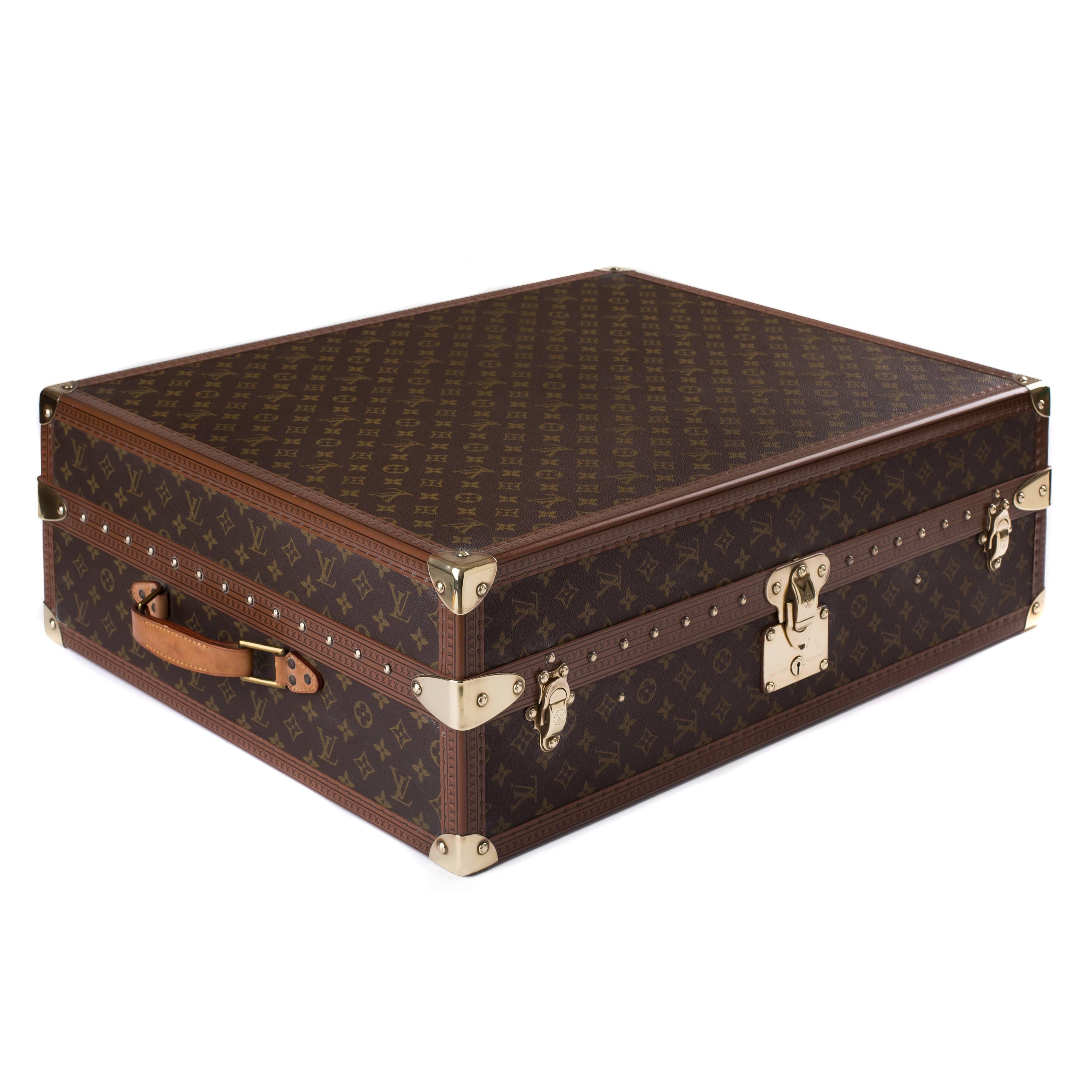 Louis Vuitton monogram shoe case with brass hardware. This functional case has space to hold 12 individual pairs of shoes, six pairs on each side.
The case is trimmed with brown leather cowhide embossed with the black LV logo. The external leather