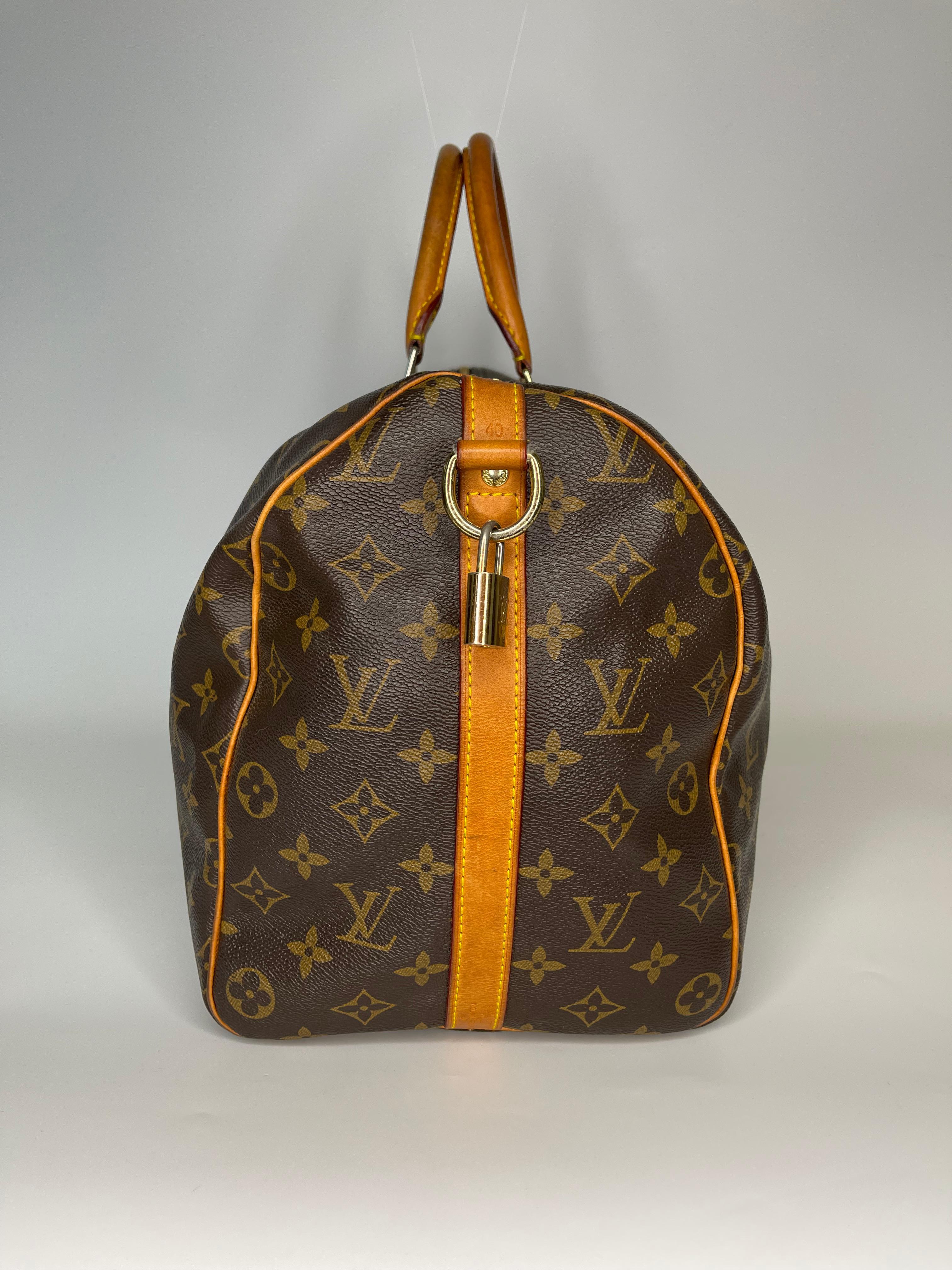 This classic Louis Vuitton bag is the Speedy Bandouliere and it is made with brown canvas with monogram print with aged natural leather finishes. This Speedy Bandouliere bag measuring 40 cm across is a discontinued style. The bag features dual top