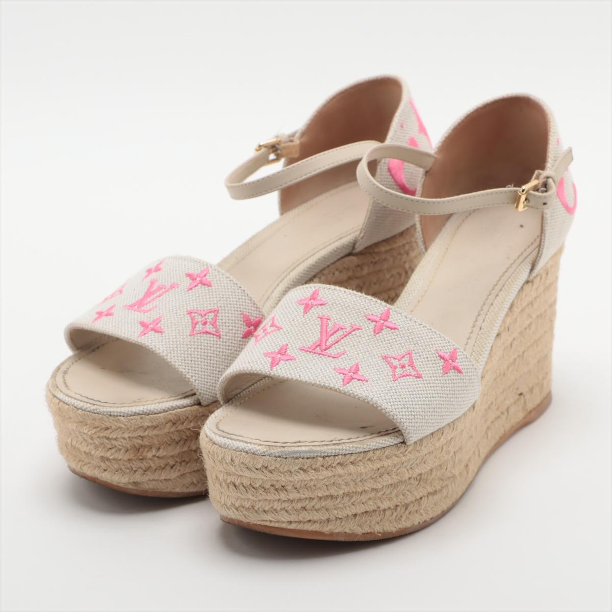 La sandale à semelle compensée Monogram de Louis Vuitton en blanc et rose est un mélange captivant de sophistication et d'espièglerie. Whiting une bride en toile monogramme blanche ornée d'un charmant motif monogramme rose, les sandales exsudent un
