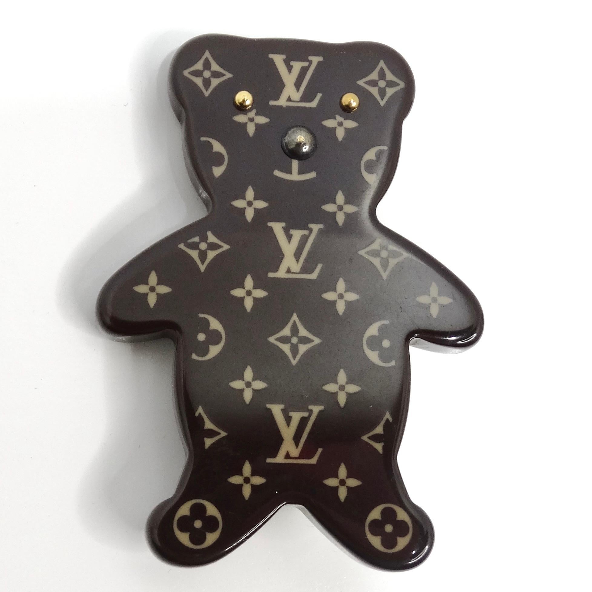 Introducing the charming Louis Vuitton Monogram Teddy Bear Brooch, a playful and luxurious accessory that adds a touch of whimsy to any ensemble. Crafted from high-quality resin, this adorable brooch is designed in the shape of a teddy bear,
