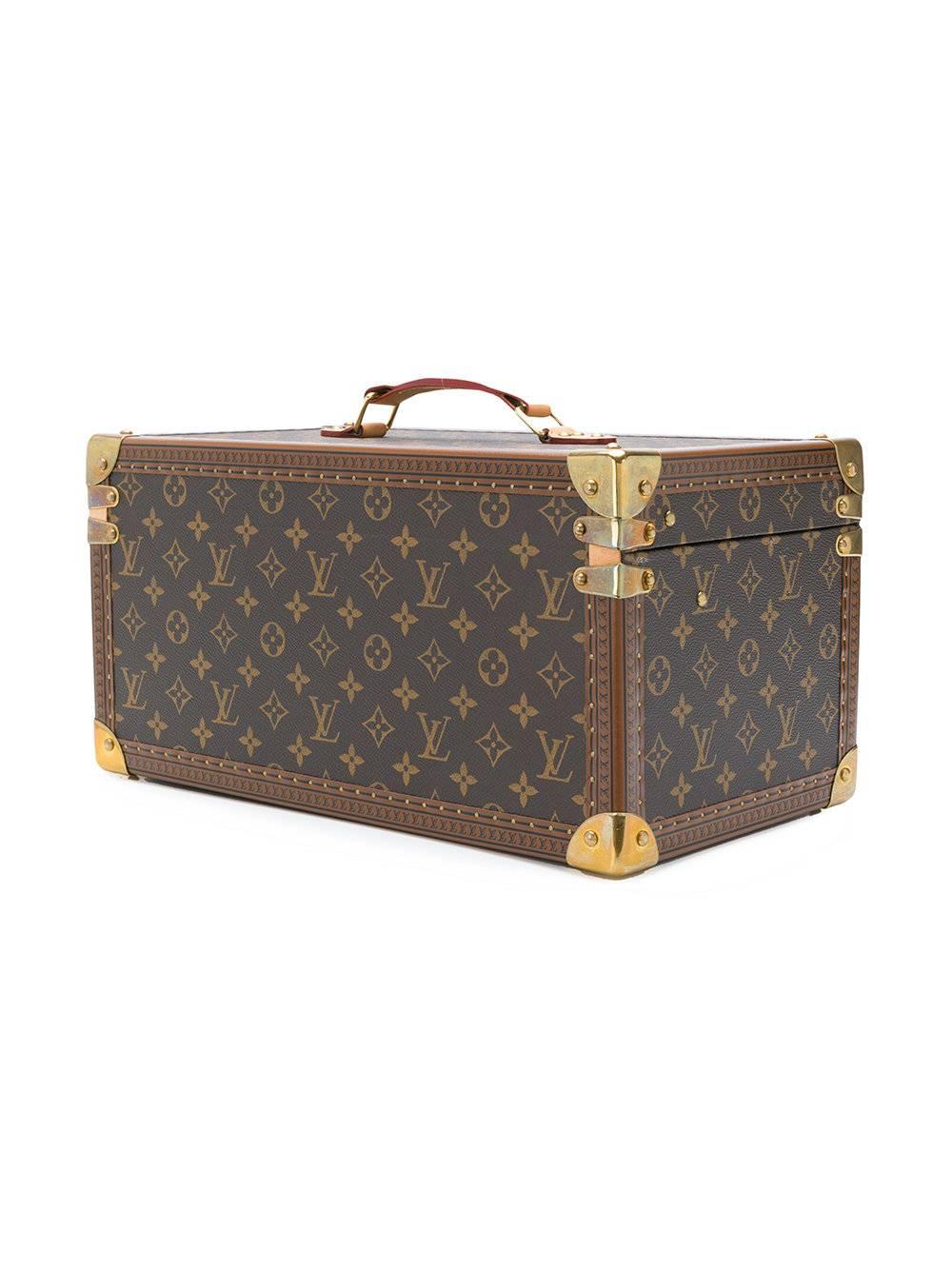 This Brown and beige leather trunk cosmetic box from Louis Vuitton Vintage featuring a flat top handle, foldover top with twist-lock closure, a clasp fastening, a main internal compartment, a monogram pattern, gold-tone hardware, a structured design
