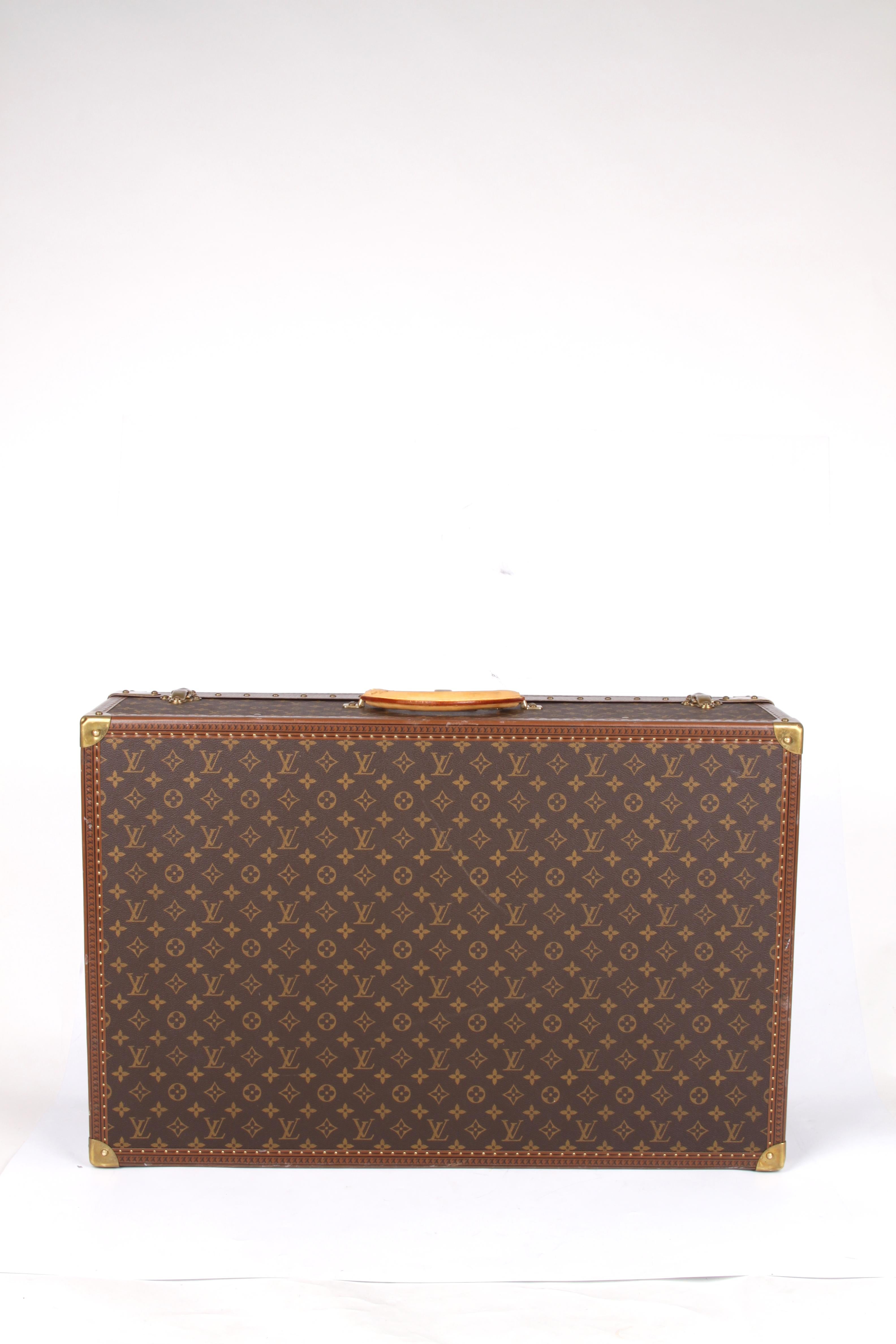 Rather large size suitcase, of course executed in the welknown dark brown canvas covered with LV monograms. Garnished with natural-tone leather and copper-tone hardware. The lid has as much as three locks, a luggage label can be found on the leather