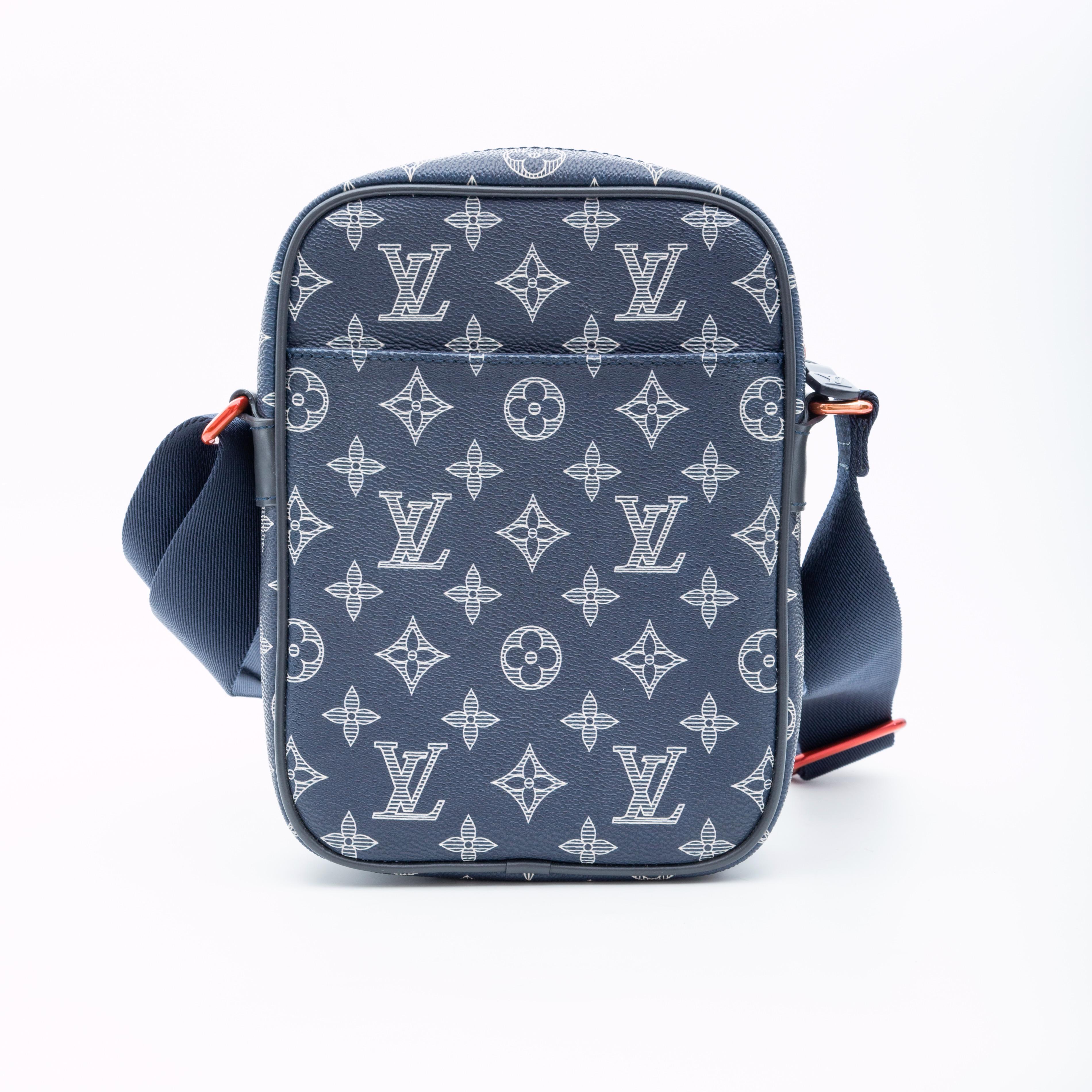 Designed by Kim Jones for the SS18 show and reflects his streetwear aesthetic. 
This messenger bag is made of monogram on dark blue/ white toile canvas. Featuring blue leather trim, a red upside down LV logo on the exterior, a waist-length blue