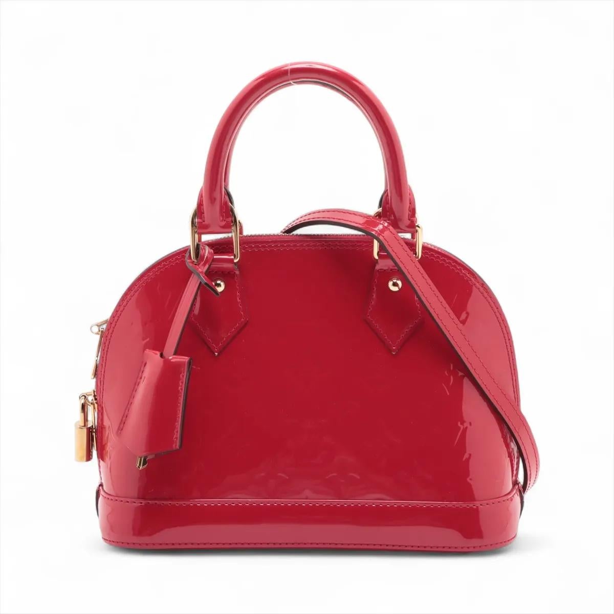 Die Louis Vuitton Monogram Vernis Alma BB in Rot ist eine auffällige und kompakte Handtasche, die zeitlose Eleganz ausstrahlt. Sie ist aus glänzendem Vernis-Lackleder gefertigt, das mit dem kultigen Monogram-Muster geprägt ist, und bietet einen