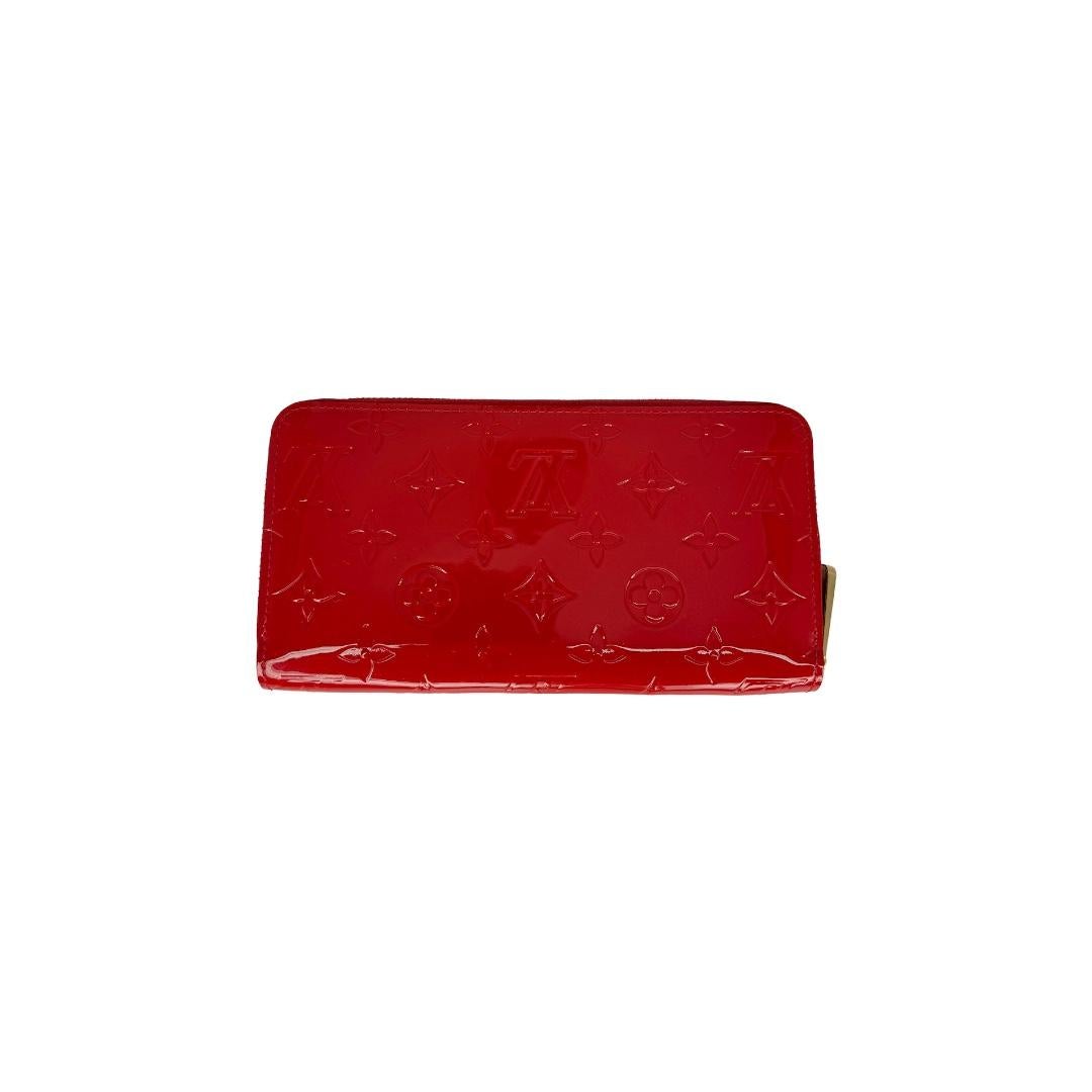 This Louis Vuitton Zippy Wallet was made in Spain of 2014 and it is finely crafted of a red Louis Vuitton Monogram Vernis Patent Leather exterior with gold-tone hardware features. It has a zipper closure that opens up to a red leather interior with