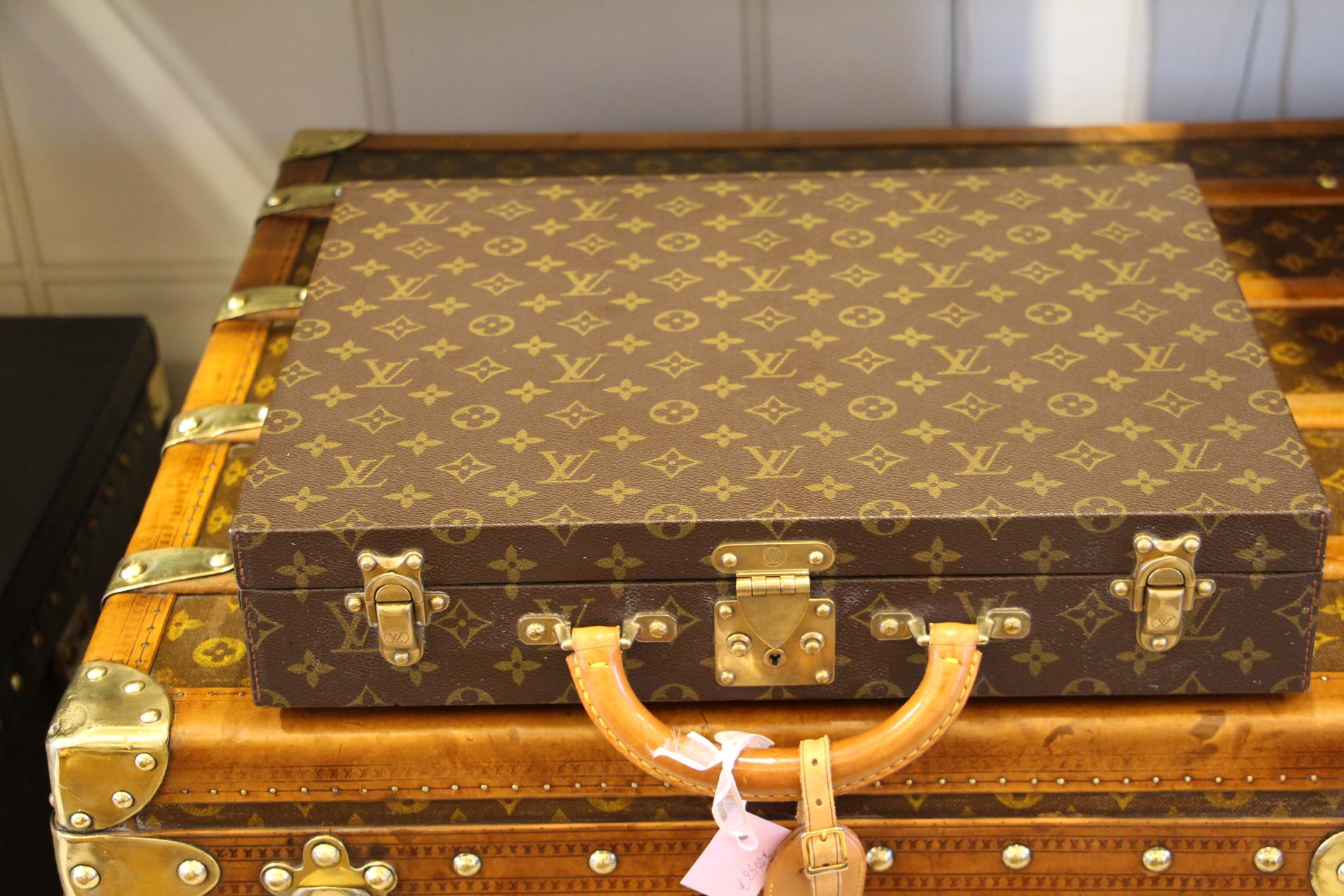 This elegant classeur briefcase features monogram canvas and a comfortable leather handle. Closed by a solid brass lock, it is accompanied by two crafted brass trunk latches. It has got its original keys.
Green interior with two pockets under its