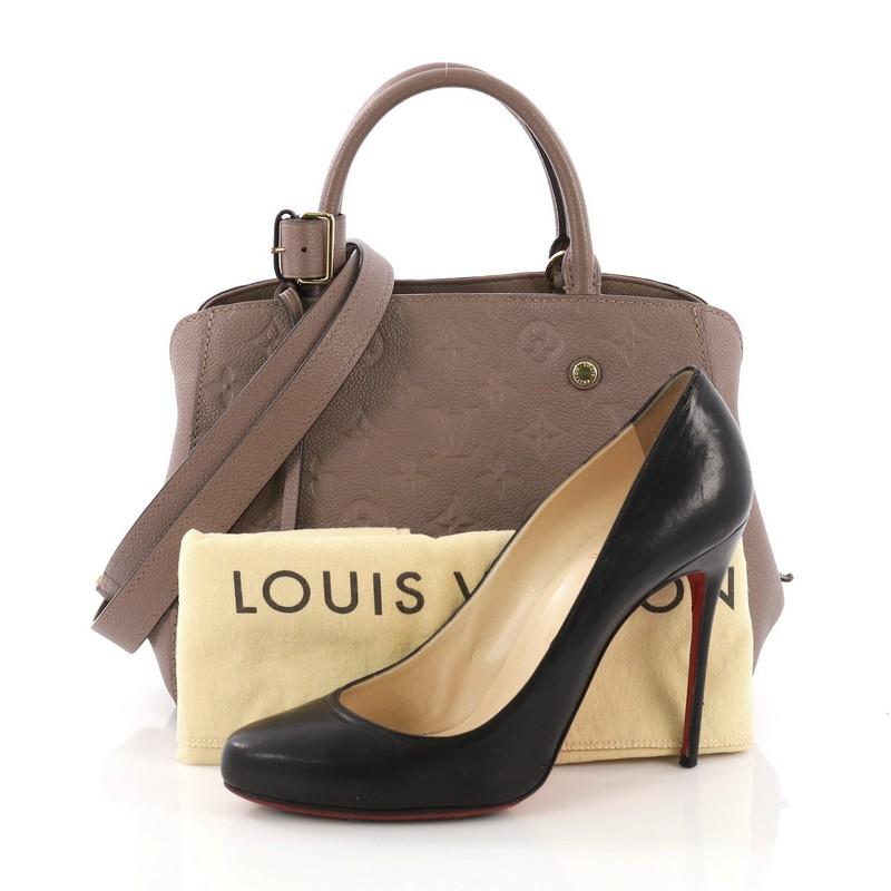 This Louis Vuitton Montaigne Handbag Monogram Empreinte Leather BB, crafted from taupe monogram empreinte leather, features dual rolled handles, protective base studs, and gold-tone hardware. Its hook closure opens to a taupe fabric interior with