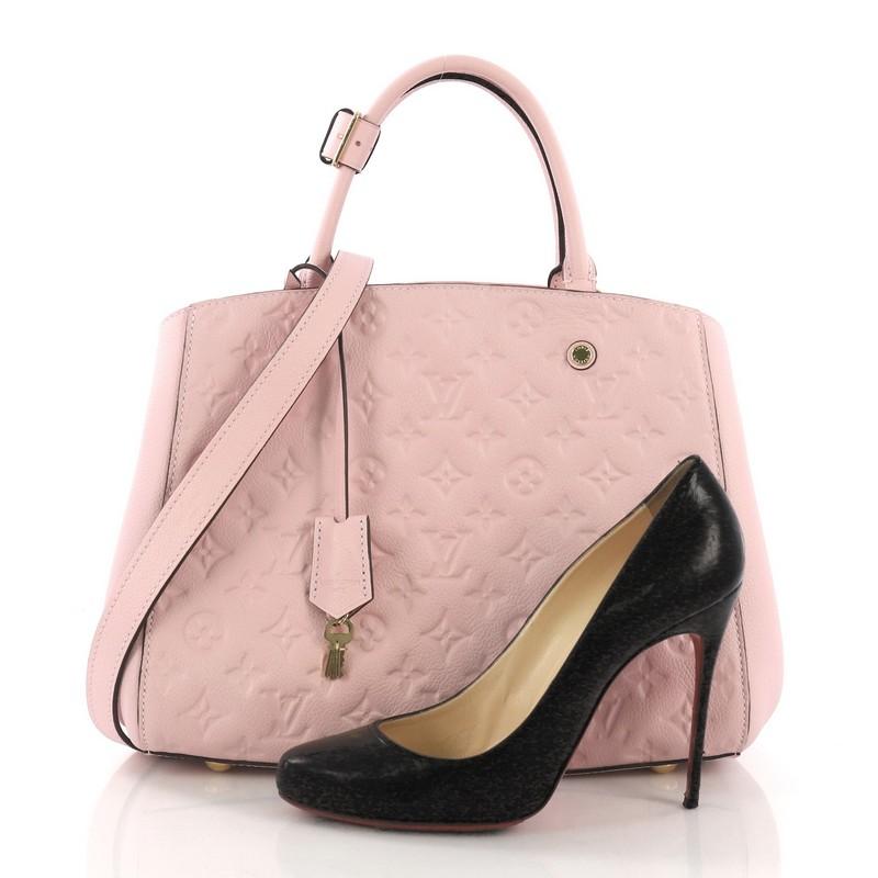 This Louis Vuitton Montaigne Handbag Monogram Empreinte Leather MM, crafted from pink monogram empreinte leather, features dual rolled handles, protective base studs, and gold-tone hardware. Its hook closure opens to a pink fabric interior with