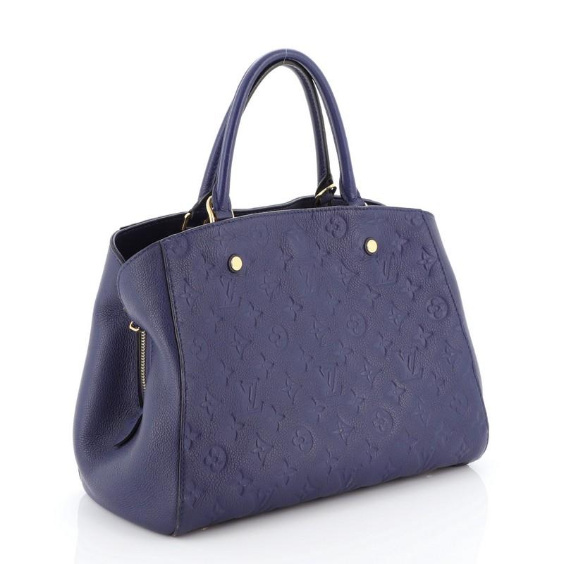 This Louis Vuitton Montaigne Handbag Monogram Empreinte Leather MM, crafted in blue monogram empreinte leather, features dual rolled leather handles, protective base studs, and gold-tone hardware. Its hook closure opens to a blue fabric interior