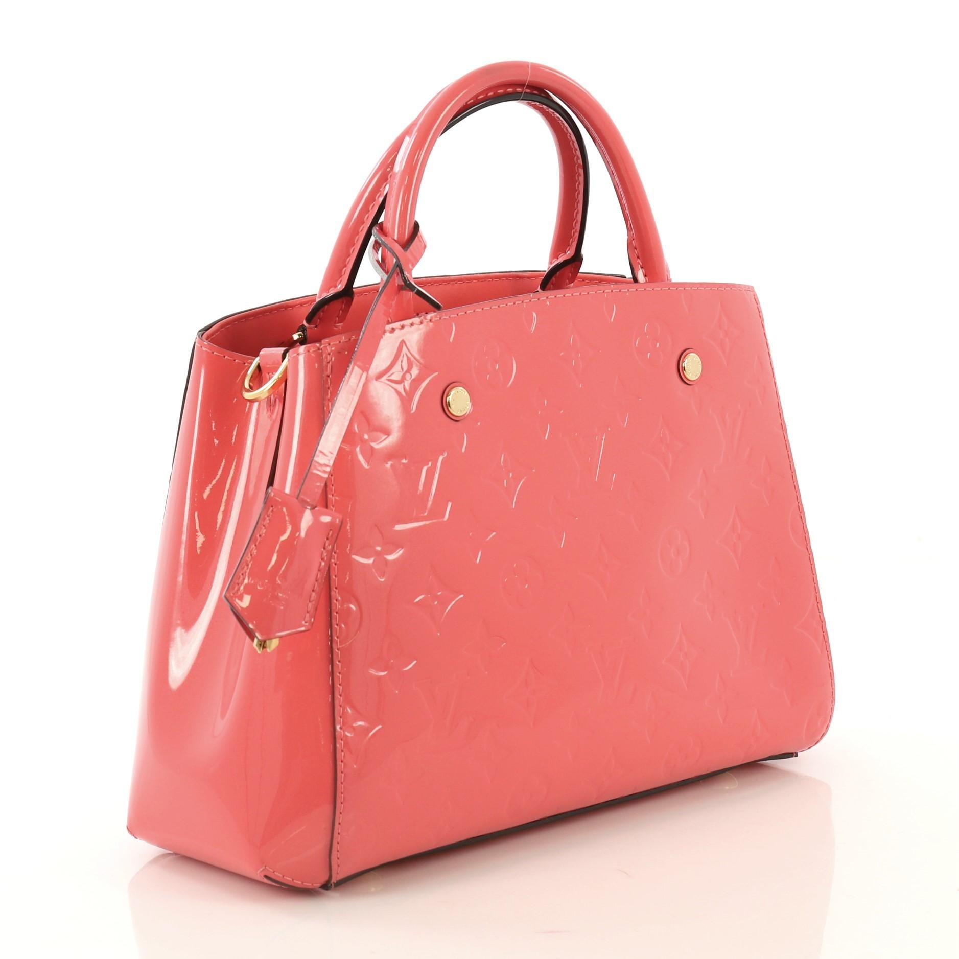 This Louis Vuitton Montaigne Handbag Monogram Vernis BB, crafted from pink monogram vernis leather, features dual rolled handles and gold-tone hardware. Its hook closure opens to a pink fabric interior divided into two compartments with middle zip