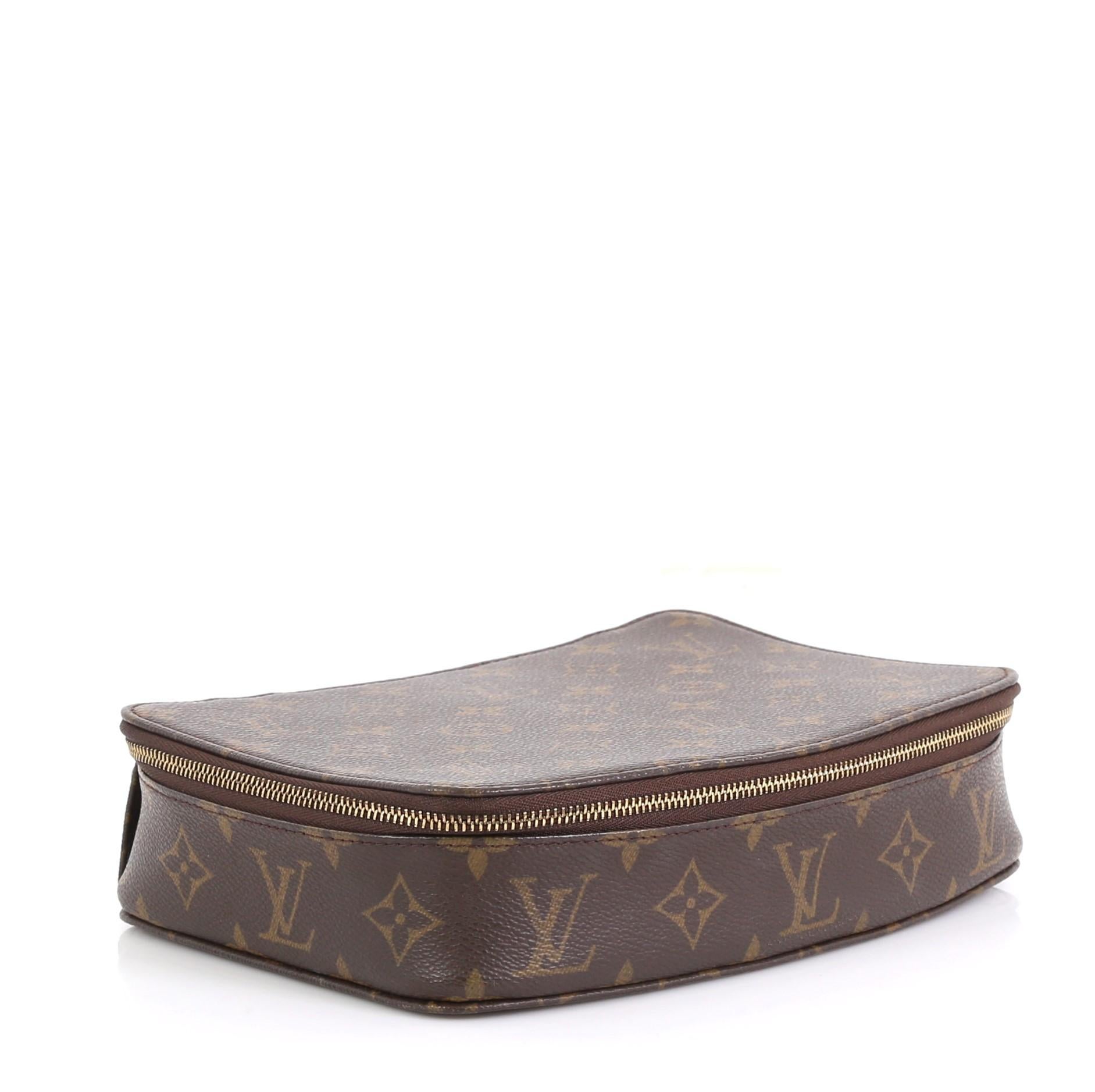 This Louis Vuitton Monte-Carlo Jewelry Box Monogram Canvas, crafted from brown monogram coated canvas, features a structured silhouette and gold-tone hardware. Its zip-around closure opens to a beige microfiber interior with multiple pouch zipped