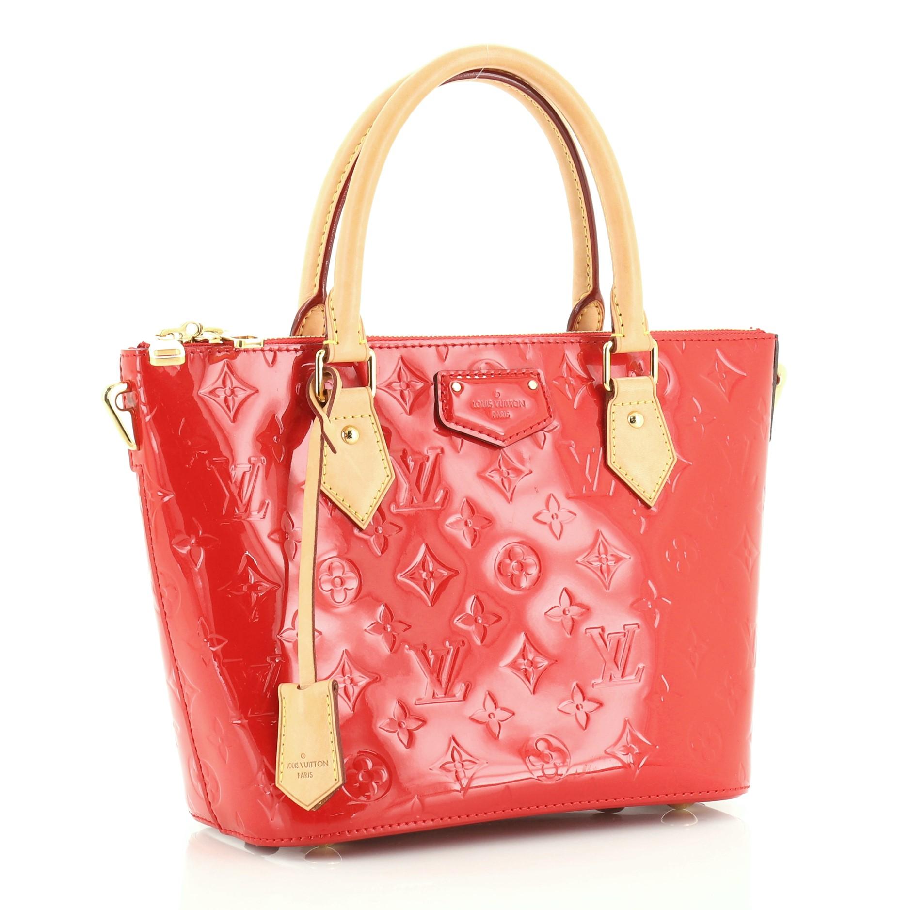 This Louis Vuitton Montebello Handbag Monogram Vernis PM, crafted in red monogram vernis leather, features dual rolled vachetta handles, protective base studs, and gold-tone hardware. Its zip closure opens to a red fabric interior with slip pocket.