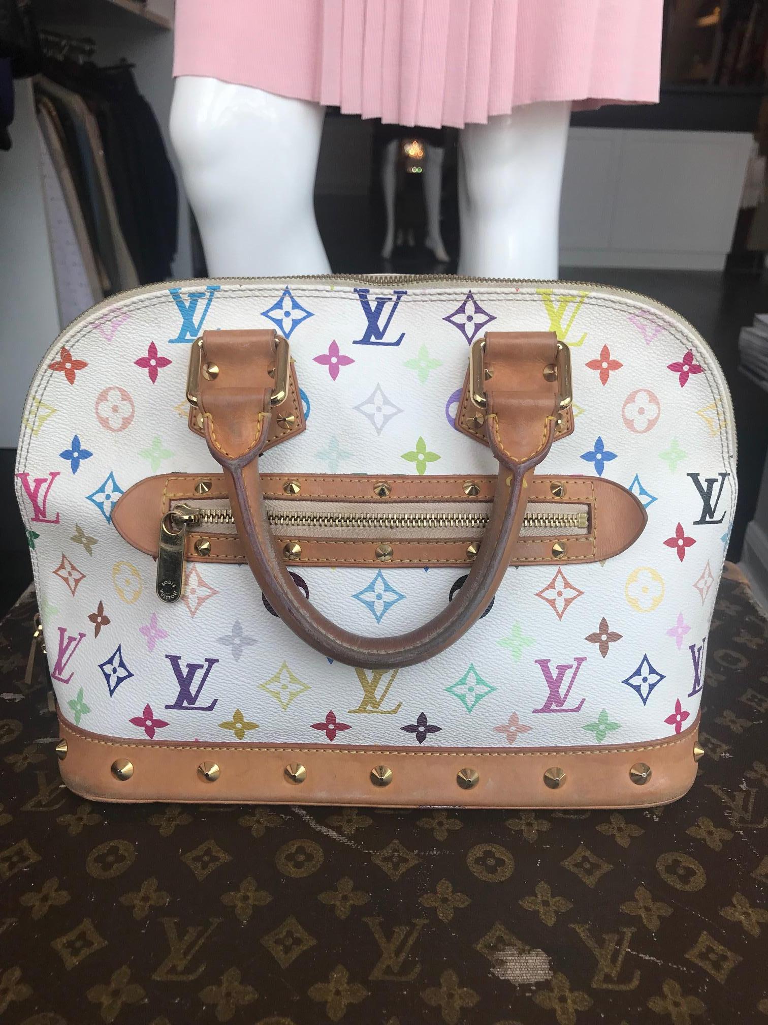 White with multicolored “LV” monogram leather. Gold-tone hardware. Tan vachetta trim and detail. Studded embellishments throughout. Top zipper closure. Dual top rolled handles. One exterior zippered pocket. Maroon lined interior. One interior phone