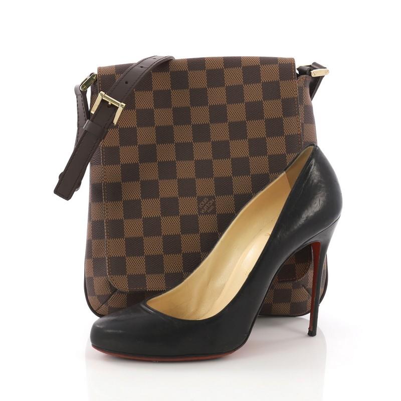 This Louis Vuitton Musette Salsa Handbag Damier, crafted in damier ebene coated canvas, features an adjustable shoulder strap and gold-tone hardware. Its magnetic snap closure opens to an orange microfiber interior with a side wall pocket.