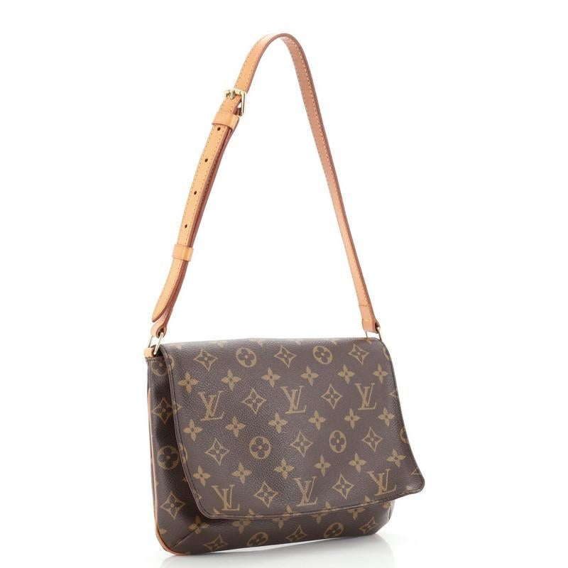 This Louis Vuitton Musette Tango Handbag Monogram Canvas, crafted from brown monogram coated canvas, features an adjustable cowhide leather strap, vachetta leather trim, and gold-tone hardware. Its magnetic snap closure opens to a brown microfiber