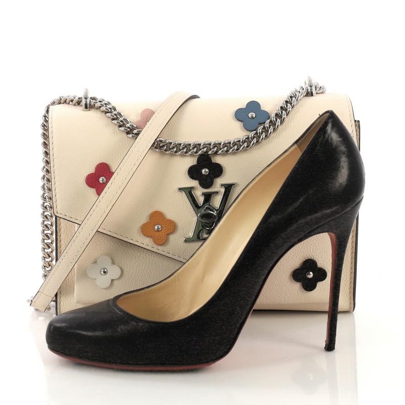 This Louis Vuitton Mylockme Handbag Flower Embellished Leather BB, crafted in beige embellished leather, features a leather top handle, exterior back zip pocket, and silver-tone hardware. It's LV twist-lock closure opens to a beige microfiber