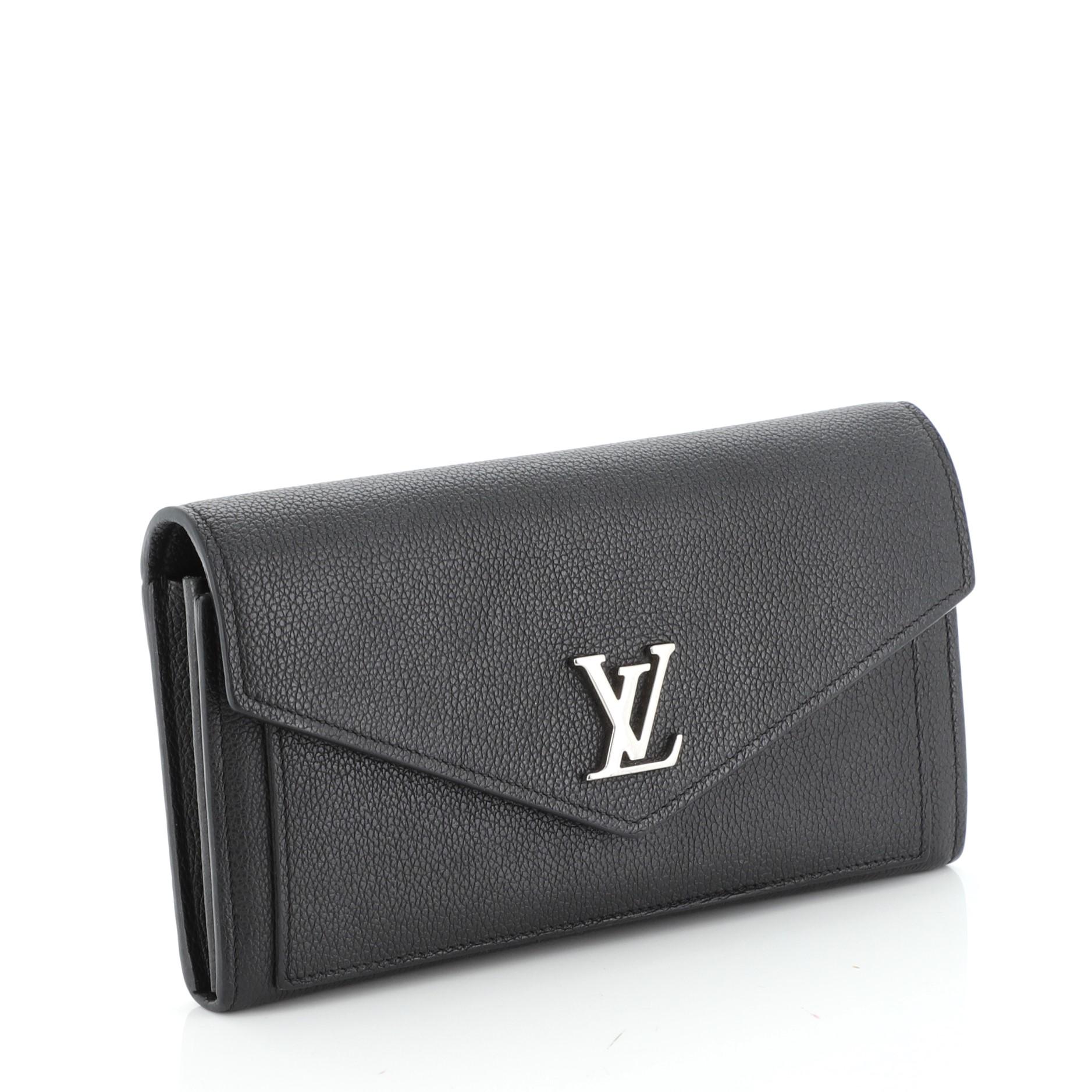 This Louis Vuitton Mylockme Wallet Leather, crafted in black leather, features silver-tone hardware. Its flap opens to a black leather and fabric interior with multiple card slots, middle zip pocket and slip pocket. Authenticity code reads: TA0129.
