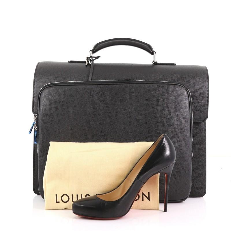 This Louis Vuitton Neo Robusto 3 Briefcase Taiga Leather, crafted in black taiga leather, features rolled and reinforced leather top handle with silver links, gusseted sides and silver-tone hardware. Its press-lock closure opens to a black fabric