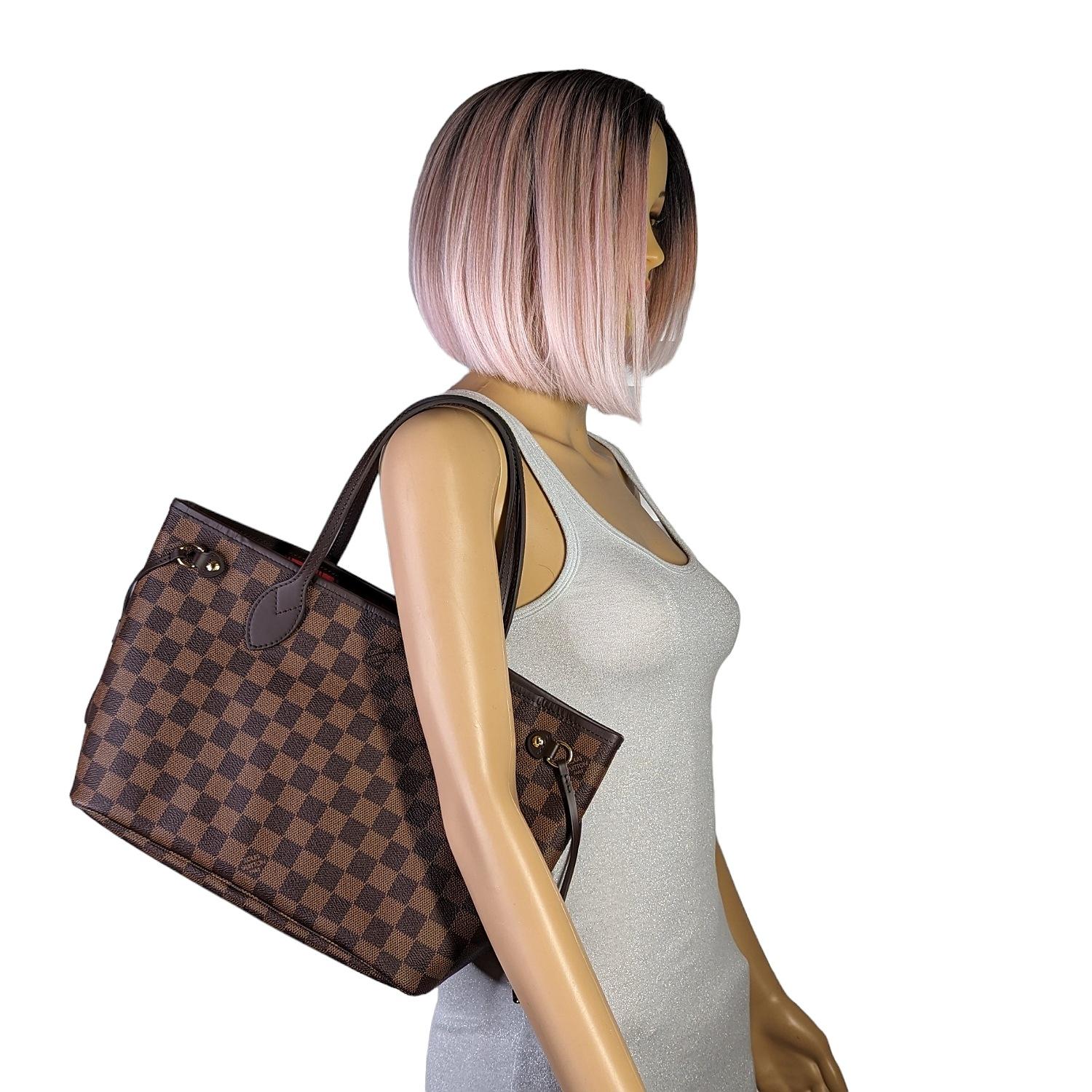 This chic tote is crafted of classic Louis Vuitton damier patterned canvas with brown cowhide leather trim including strap handles. The top is open to a rouge red striped fabric interior with a hanging zipper pocket and match pochette. Est. Retail