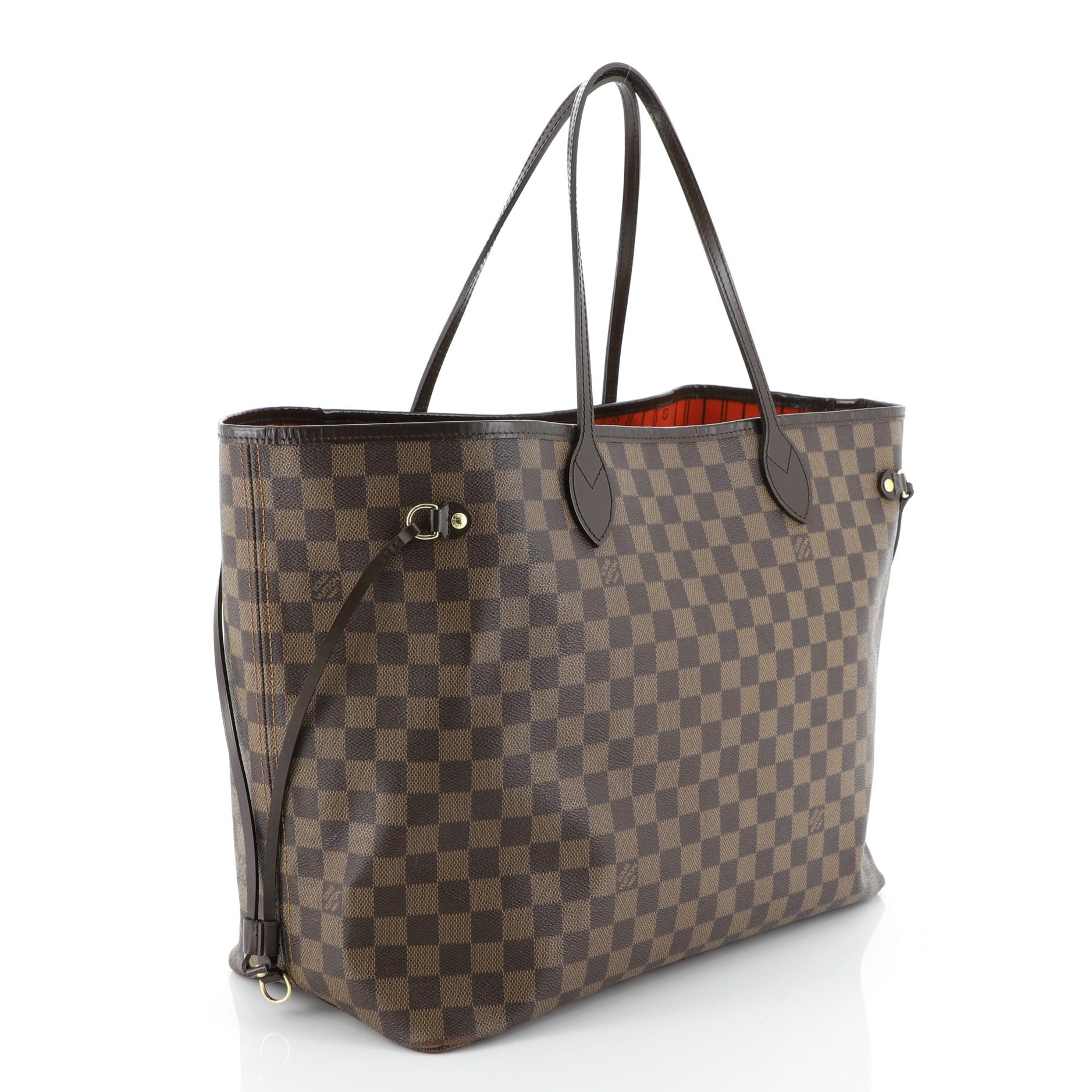 This Louis Vuitton Neverfull Tote Damier GM is a classic piece launched in 2007. Crafted in damier ebene coated canvas, it features dual slim handles, side laces, and gold-tone hardware. Its wide open top showcases a red fabric interior with side