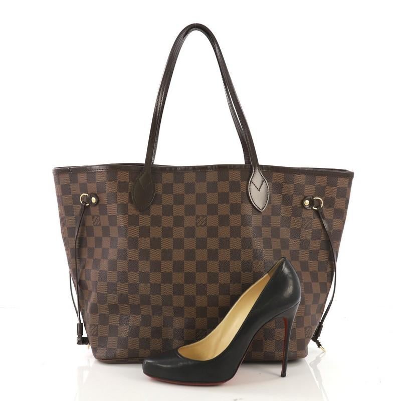 This Louis Vuitton Neverfull Tote Damier MM, crafted in damier ebene coated canvas, features dual slim handles, side laces, and gold-tone hardware. Its wide open top showcases a red fabric interior with side zip pocket. Authenticity code reads: