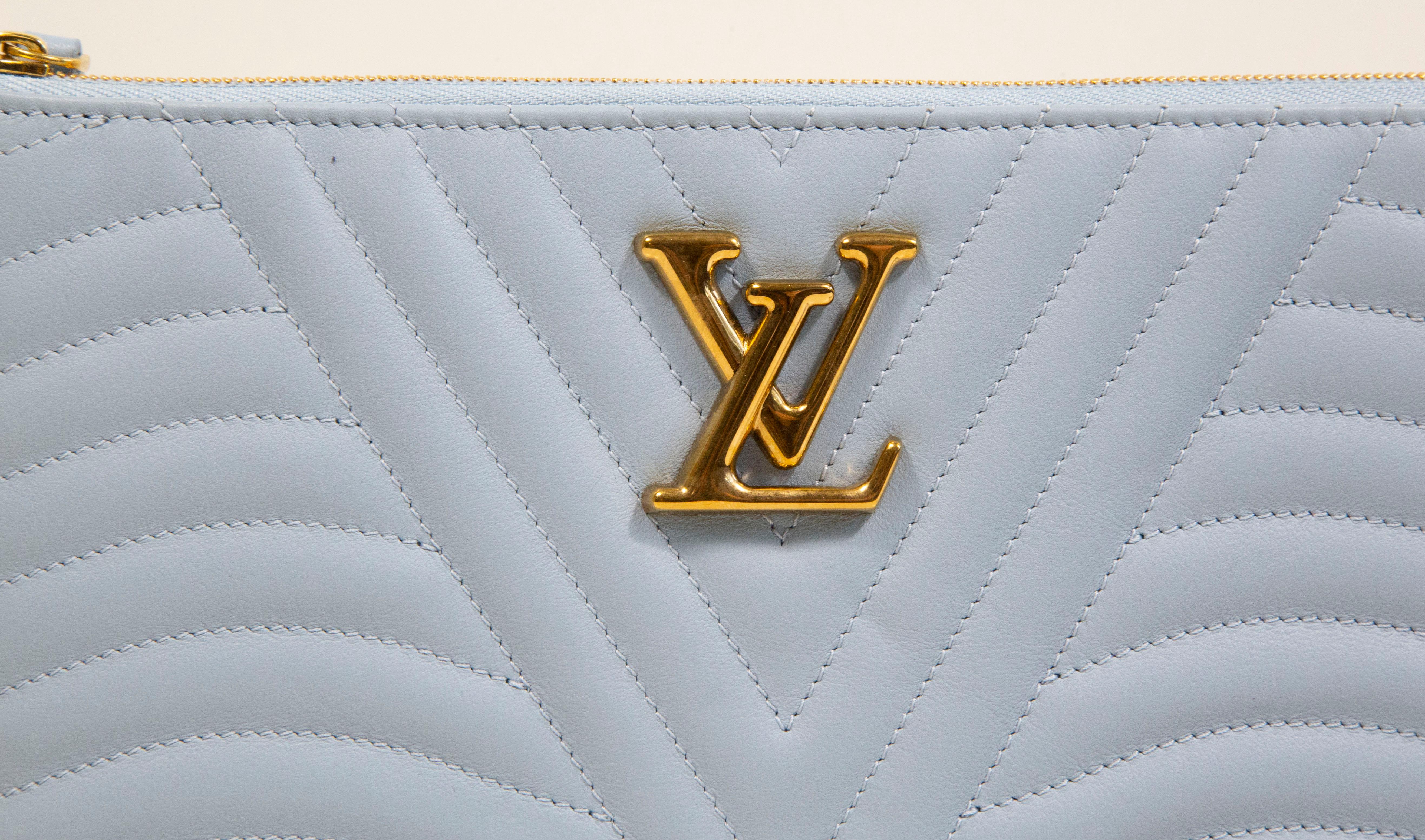 A Louis Vuitton New Wave Zip Pochette in Porcelain Blue leather with gold toned hardware. The interior is lined with blue Vachetta fabric,  Next to the major compartment, the pochette features one larger slide pocket and three slots for cards. It
