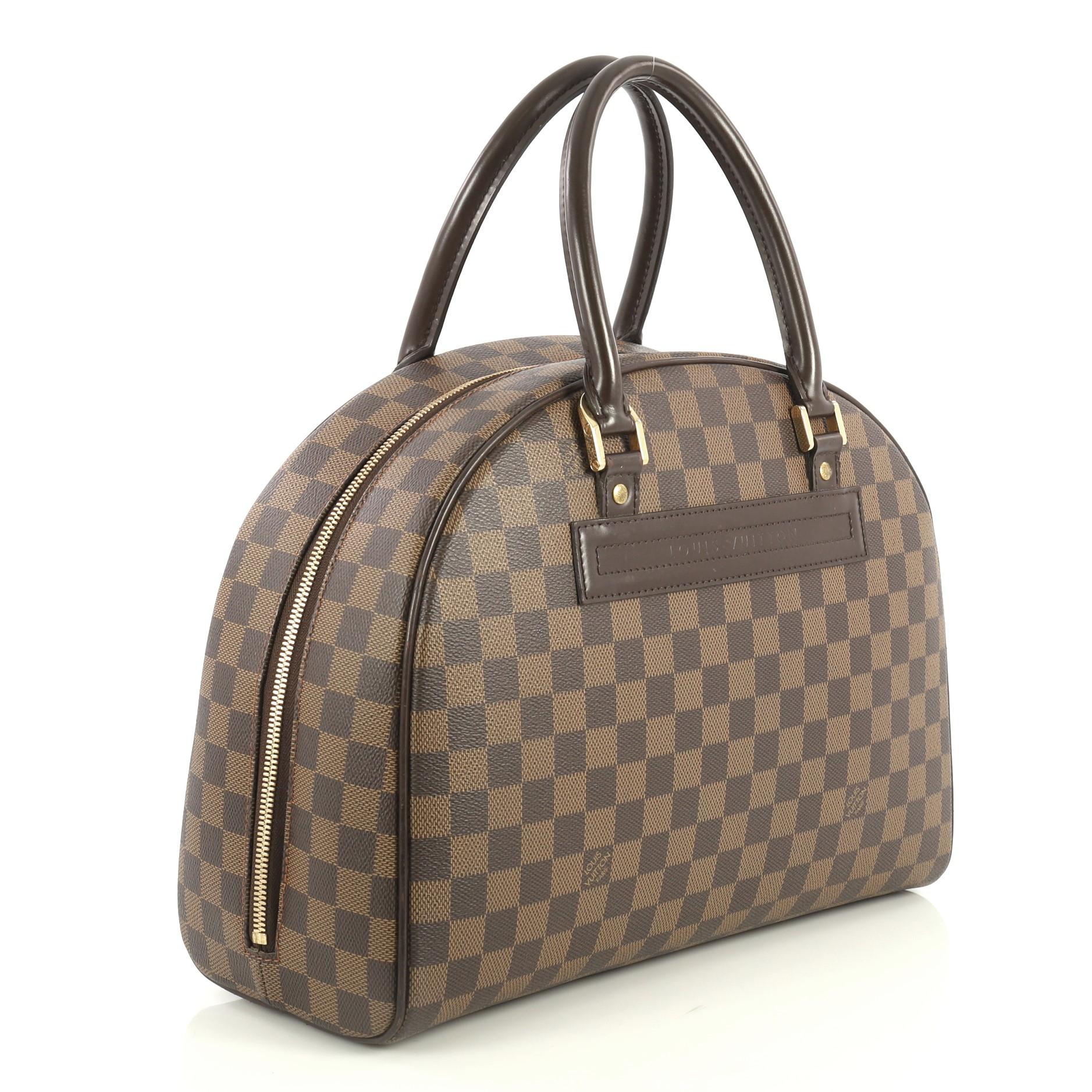 This Louis Vuitton Nolita Satchel Damier, crafted in damier ebene coated canvas, features dual rolled handles, leather trim, embossed logo in brown leather, and gold-tone hardware. Its zip closure opens to a red fabric interior with side zip and