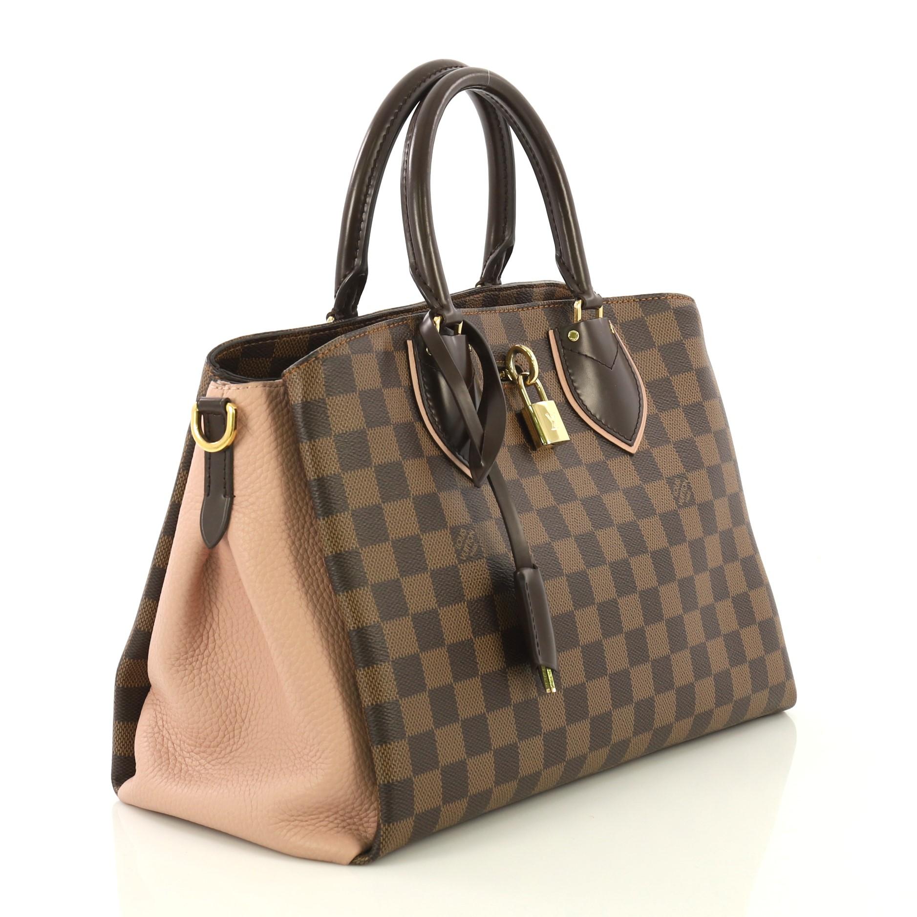 This Louis Vuitton Normandy Handbag Damier, crafted in damier ebene coated canvas, features dual rolled leather handles, leather side wings, front compartment with lock closure, and gold-tone hardware. Its middle zip compartment opens to a pink