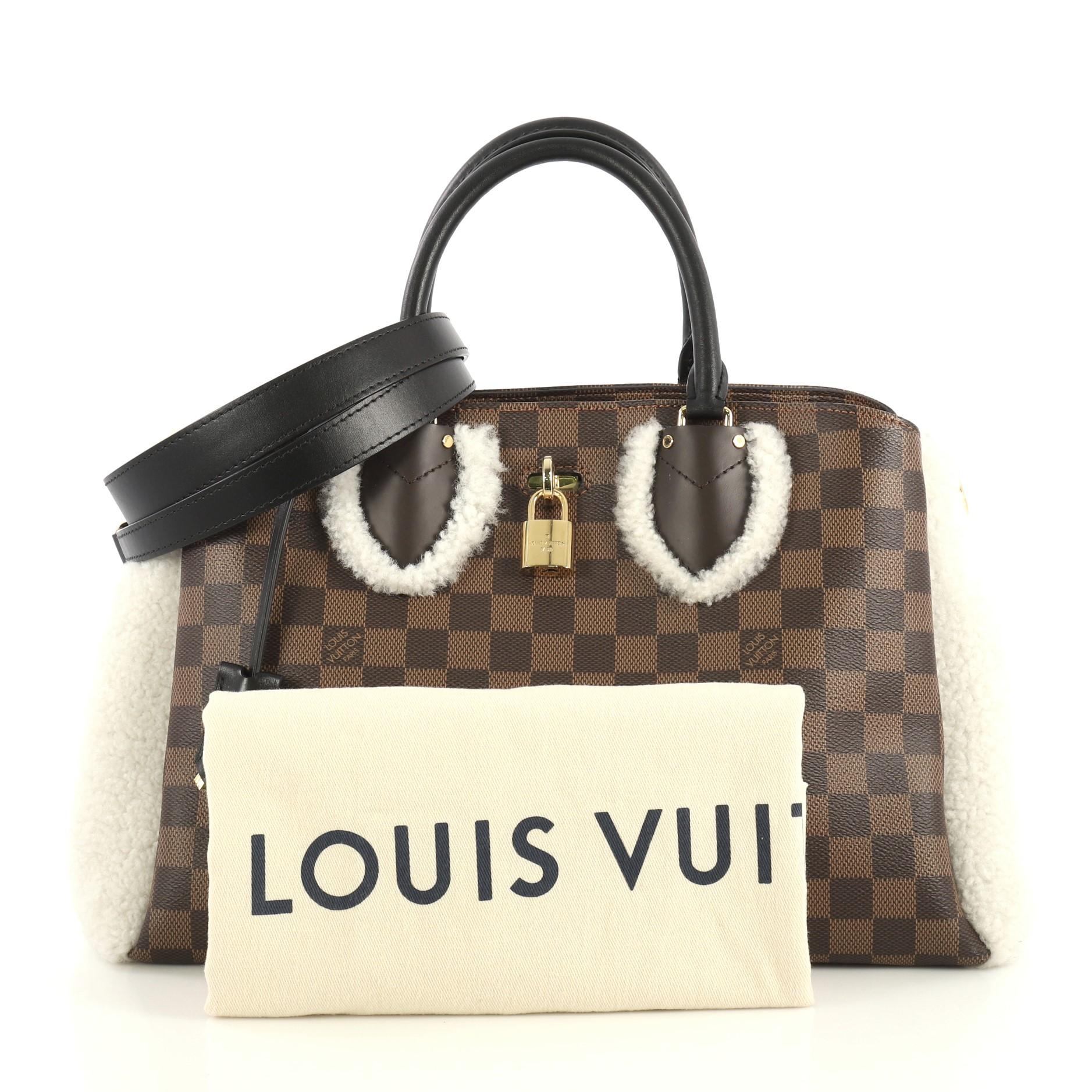 This Louis Vuitton Normandy Handbag Damier with Shearling, crafted in damier ebene coated canvas and white shearling, features dual rolled leather handles, shearling side wings, front compartment with lock closure, and gold-tone hardware. Its middle