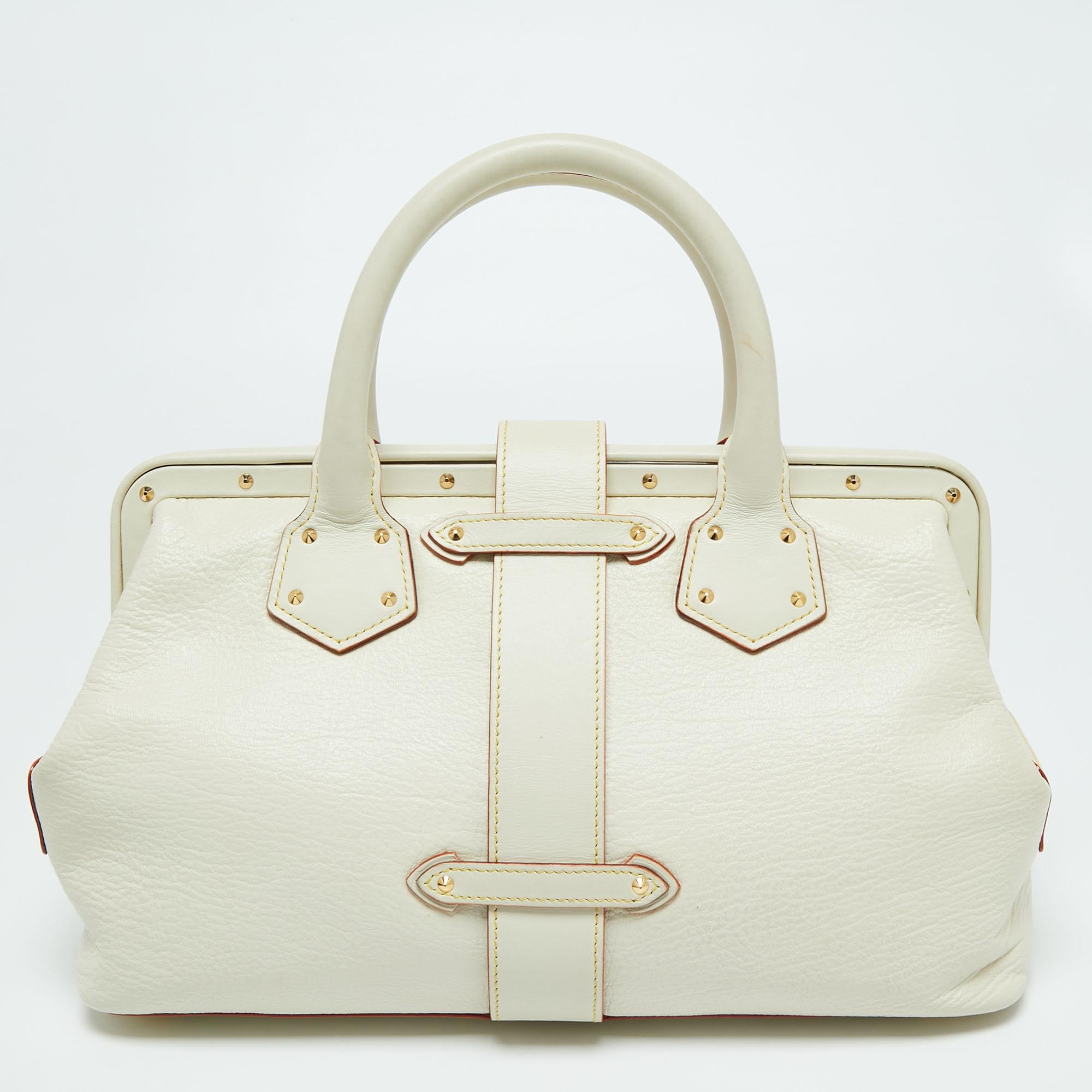 This Louis Vuitton Lingenieux PM bag is crafted to perfection. This off-white Suhali leather bag is adorned with gold-tone studs, a signature lock with the Louis Vuitton insignia, and side zip pockets. The interior is lined with fabric. The rolled