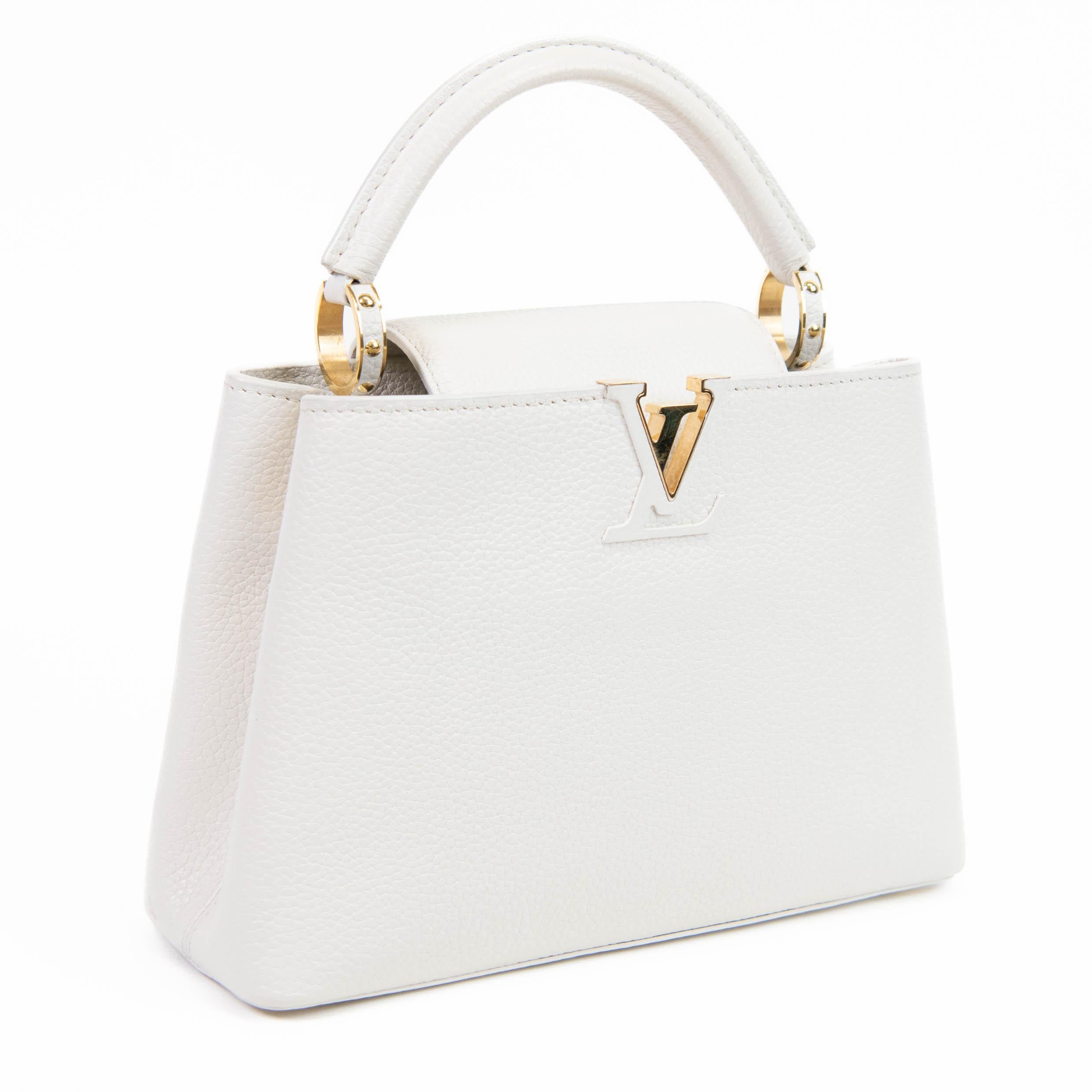 100% Authentic

This stylish handbag tote is crafted of beautifully textured taurillon calfskin leather in white. The bag features a reinforced looping rolled leather top handle with gold ring links, an optional shoulder strap, and a leather-lined