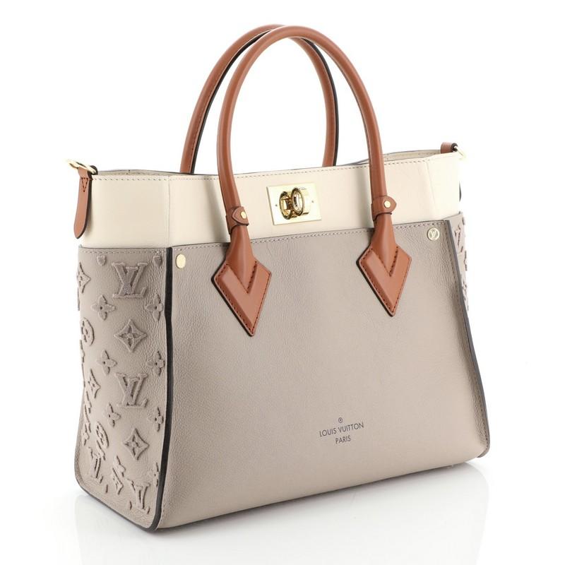 This Louis Vuitton On My Side Tote Monogram Tuffetage, crafted from neutral monogram tuffetage leather, features dual rolled handles and gold-tone hardware. Its turn-lock closure opens to a neutral microfiber interior with side zip and slip pockets.