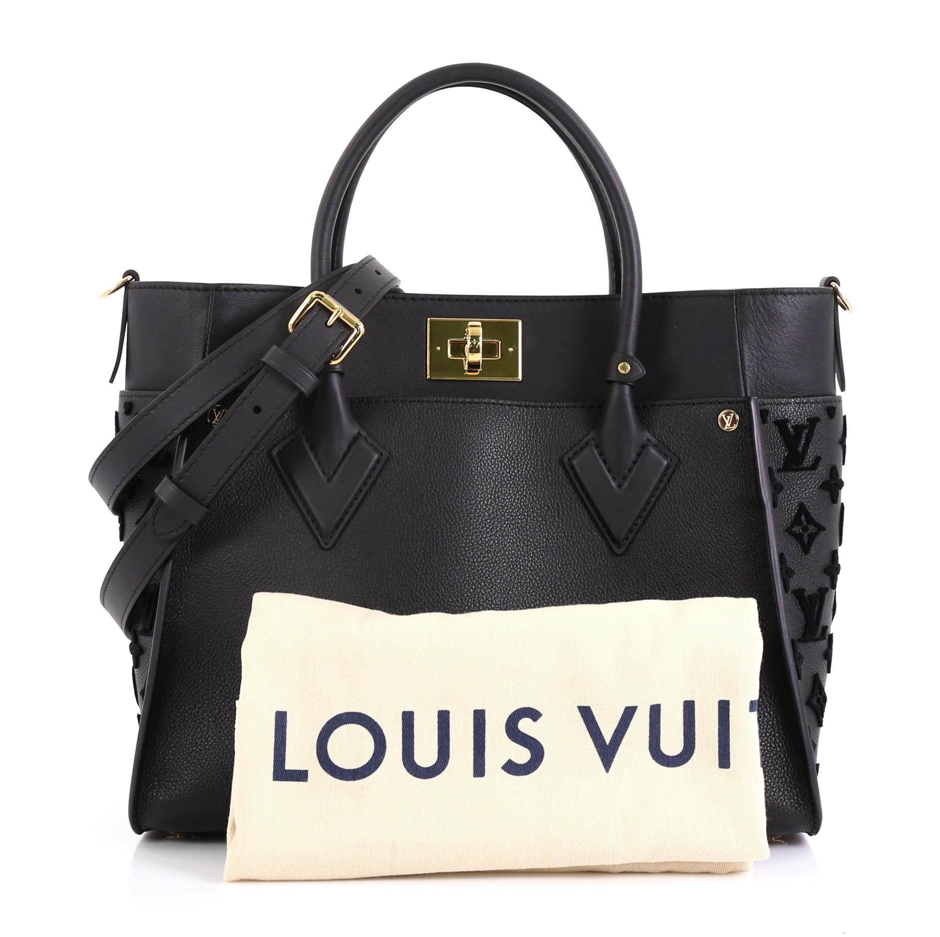 This Louis Vuitton On My Side Tote Monogram Tuffetage, crafted from black leather, features dual rolled handles and gold-tone hardware. Its turn-lock closure opens to a yellow microfiber interior with side zip and slip pockets. Authenticity code