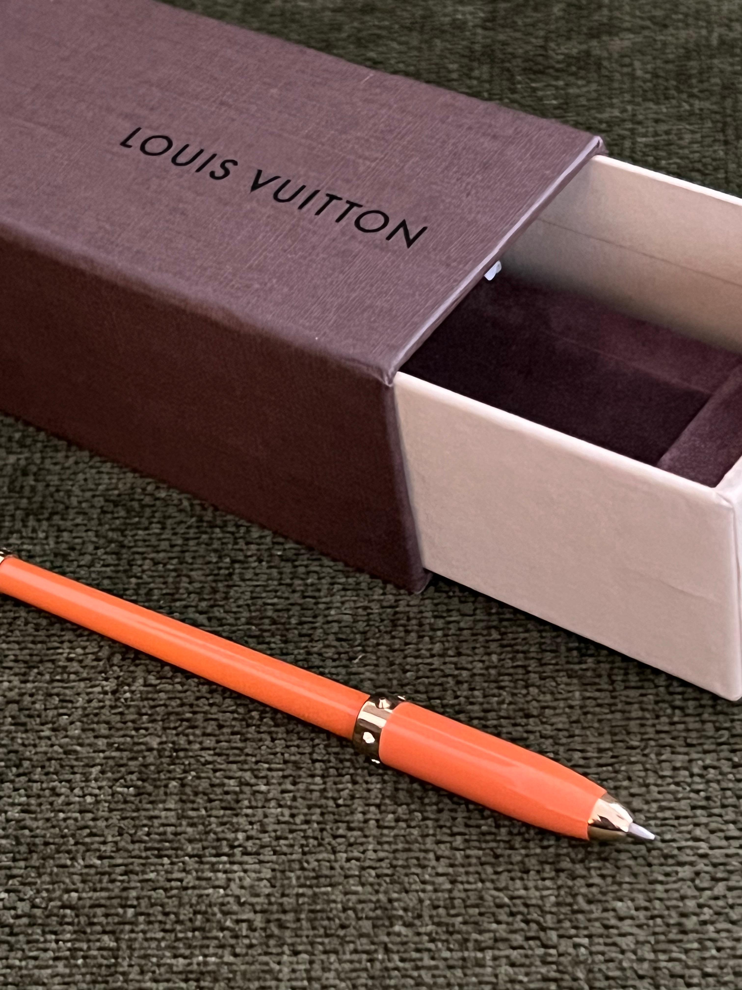 Louis Vuitton pen made to fit in the smaller-than-usual pen holders in the agendas. 
It is Orange& Gold which has a faux lid, the pen actually comes out through the tip of the pen when you twist the bottom of it.
It comes with the original box and