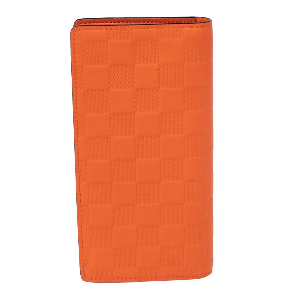 Sleek and stylish, this Brazza wallet from the House of Louis Vuitton will be your favorite accessory in no time! It is created using orange Damier leather on the exterior. It flaunts silver-tone hardware and a leather-lined interior. This stunning