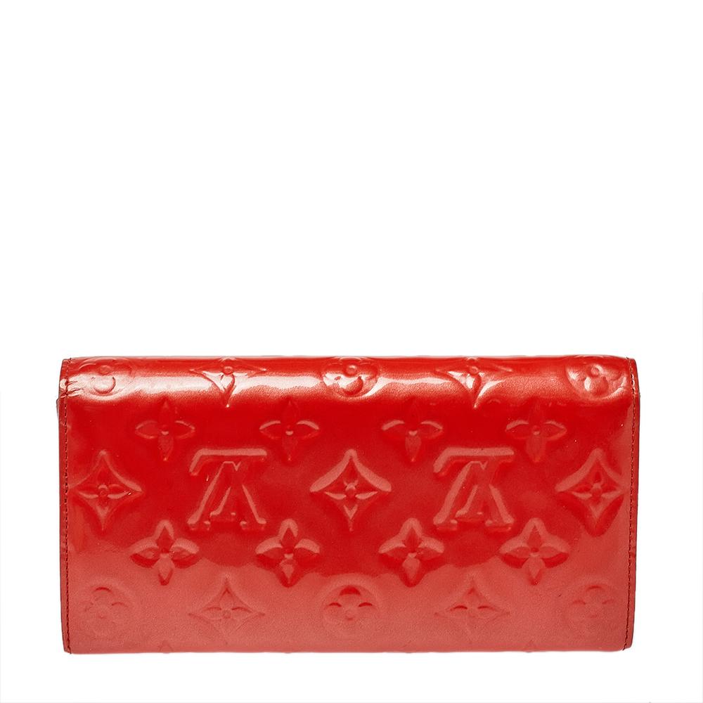 Uno dei portafogli più famosi di Louis Vuitton è il Sarah. Questo modello è realizzato in Vernis monogram e il bottone sulla patta si apre su un interno con più scomparti per carte e una tasca con zip. Di dimensioni perfette, questo portafoglio può