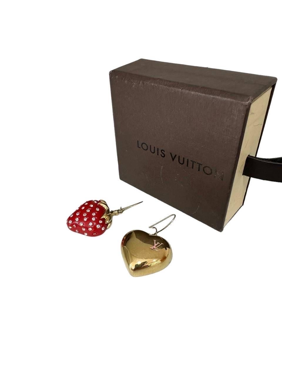 Orecchini firmati Louis Vuitton, realizzati in metallo color oro. Ils sont caractérisés par une forme a cuore d'un côté et une forme fragola ricoperta da strass de l'autre. Ils se présentent en bon état, avec une légère usure au niveau du dos.