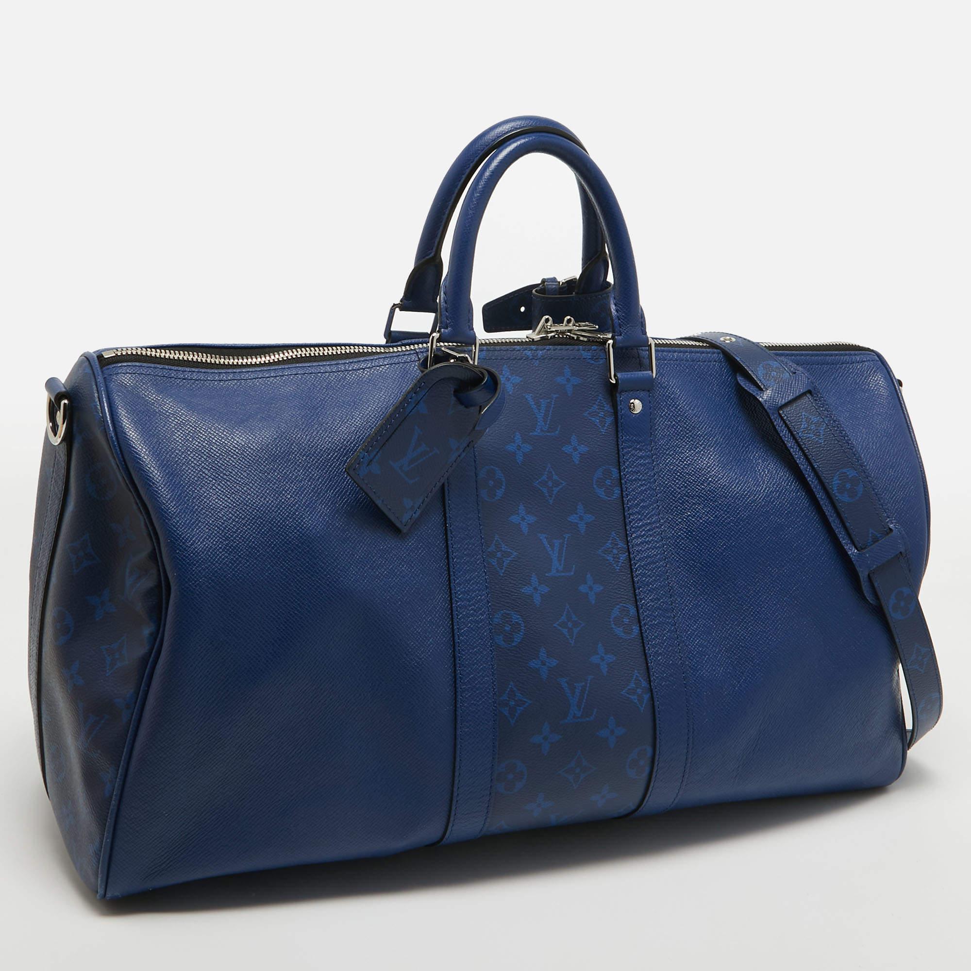 The Louis Vuitton Keepall Bandouliere 50 is a luxurious travel companion. Its exquisite design combines durable taiga leather in a striking Pacific Blue hue with the iconic Monogram Eclipse canvas. The spacious interior, reinforced leather handles,