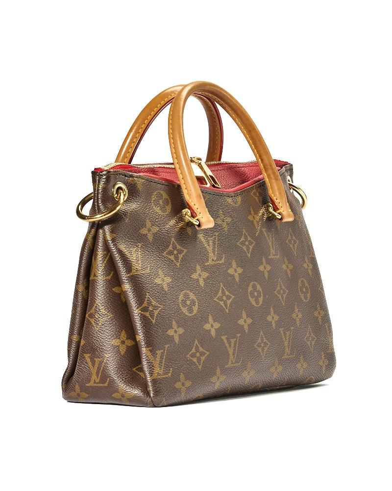 Louis Vuitton signature bag, Pallas model in size BB, made of brown canvas in classic monogram pattern with red leather inserts and gold hardware. Featuring a top zipper closure, internally lined in red suede fabric with convenient pocket, the bag