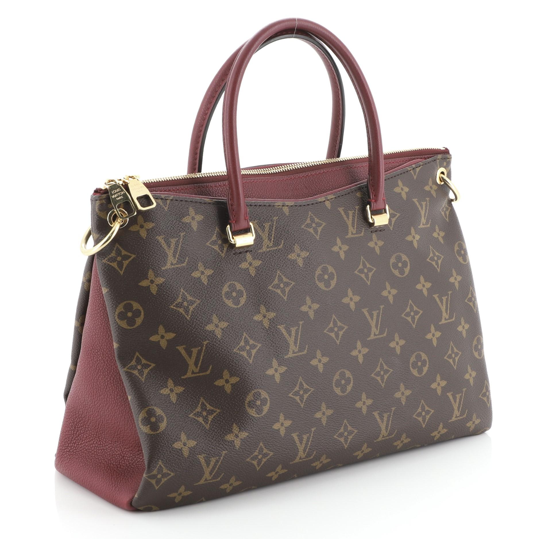 This Louis Vuitton Pallas Tote Monogram Canvas, crafted from brown monogram coated canvas and red leather, features dual rolled handles, protective base studs, and gold-tone hardware. Its two-way zip closure opens to a red microfiber interior with