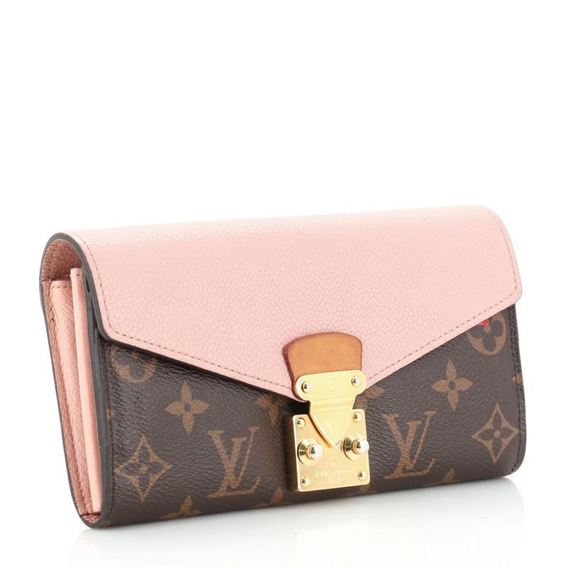 This Louis Vuitton Pallas Wallet Monogram Canvas and Calf Leather, crafted in brown monogram coated canvas and pink calf leather, features gold-tone hardware. Its S-lock closure opens to a brown monogram coated canvas and pink leather interior with