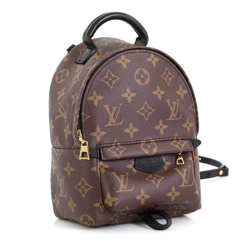 This Louis Vuitton Palm Springs Backpack Monogram Canvas Mini, crafted from brown monogram coated canvas, features a padded leather top handle, adjustable backpack shoulder straps, exterior front zip pocket, foam backing, and gold-tone hardware. Its