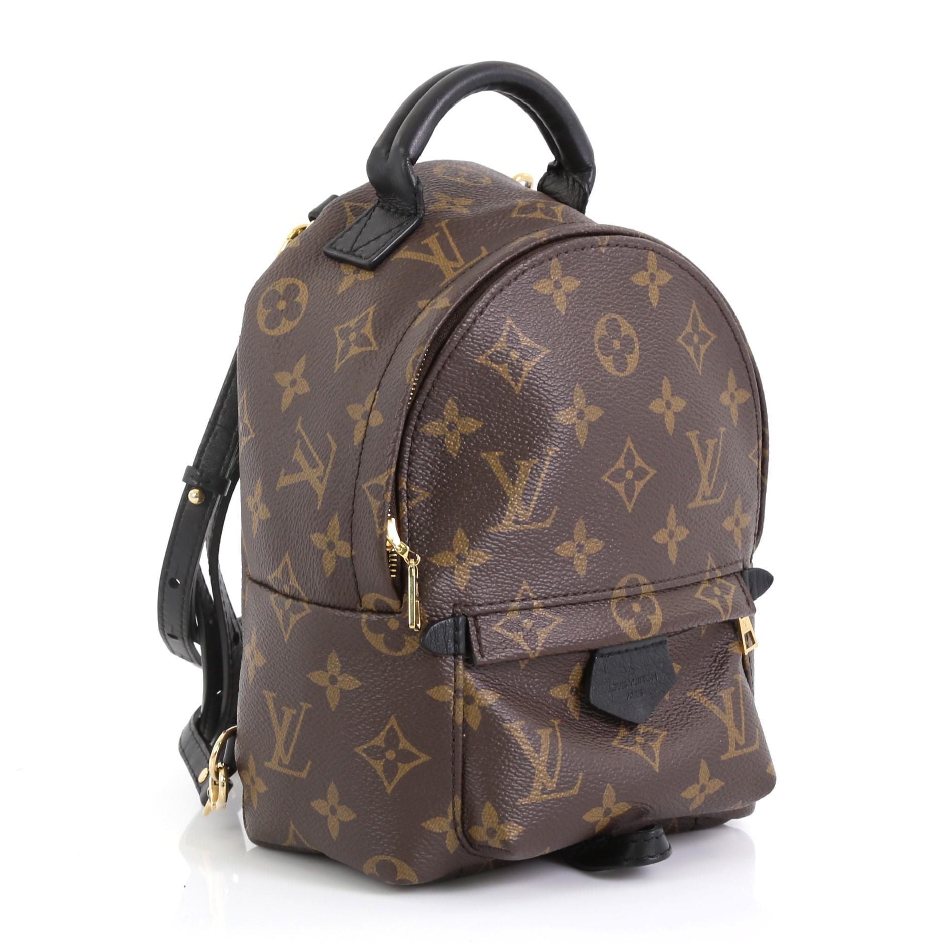 This Louis Vuitton Palm Springs Backpack Monogram Canvas Mini, crafted from brown monogram coated canvas, features a padded leather top handle, adjustable backpack shoulder straps, exterior front zip pocket, foam backing, and gold-tone hardware. Its